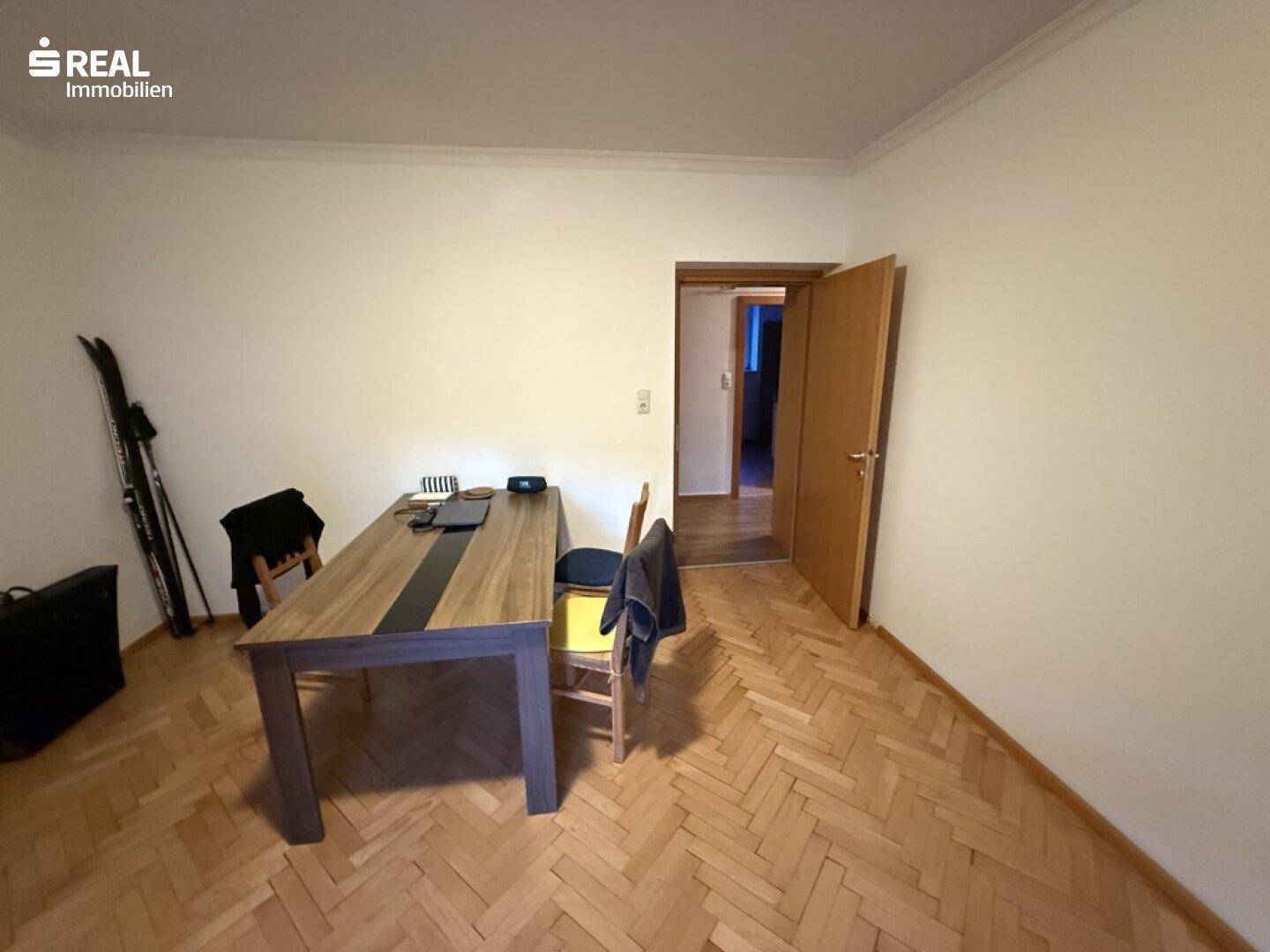 Heller Essbereich mit klassischem Fischgrätparkettboden und Holztisch.