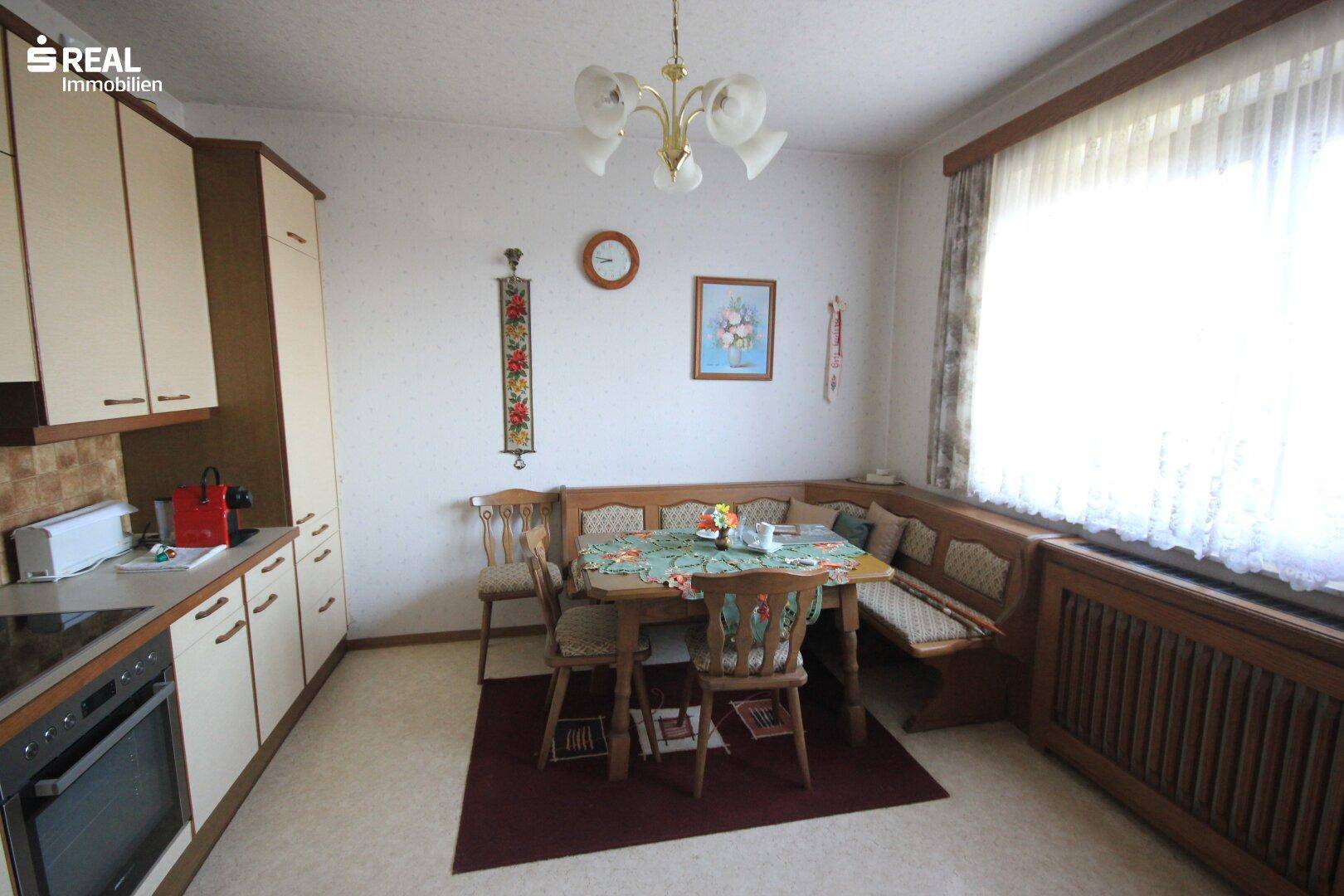 Gemütliche Wohnküche mit Essecke, Fenster und traditionellen Holzmöbeln.