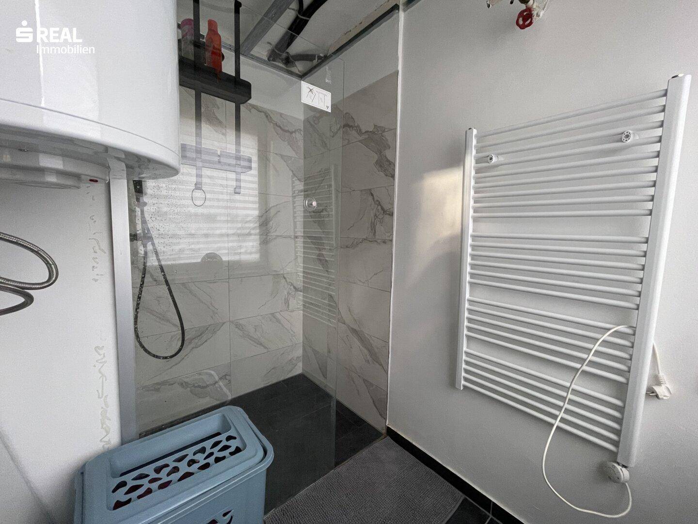 Modernes Badezimmer mit begehbarer Dusche, beheiztem Handtuchhalter und Boiler.