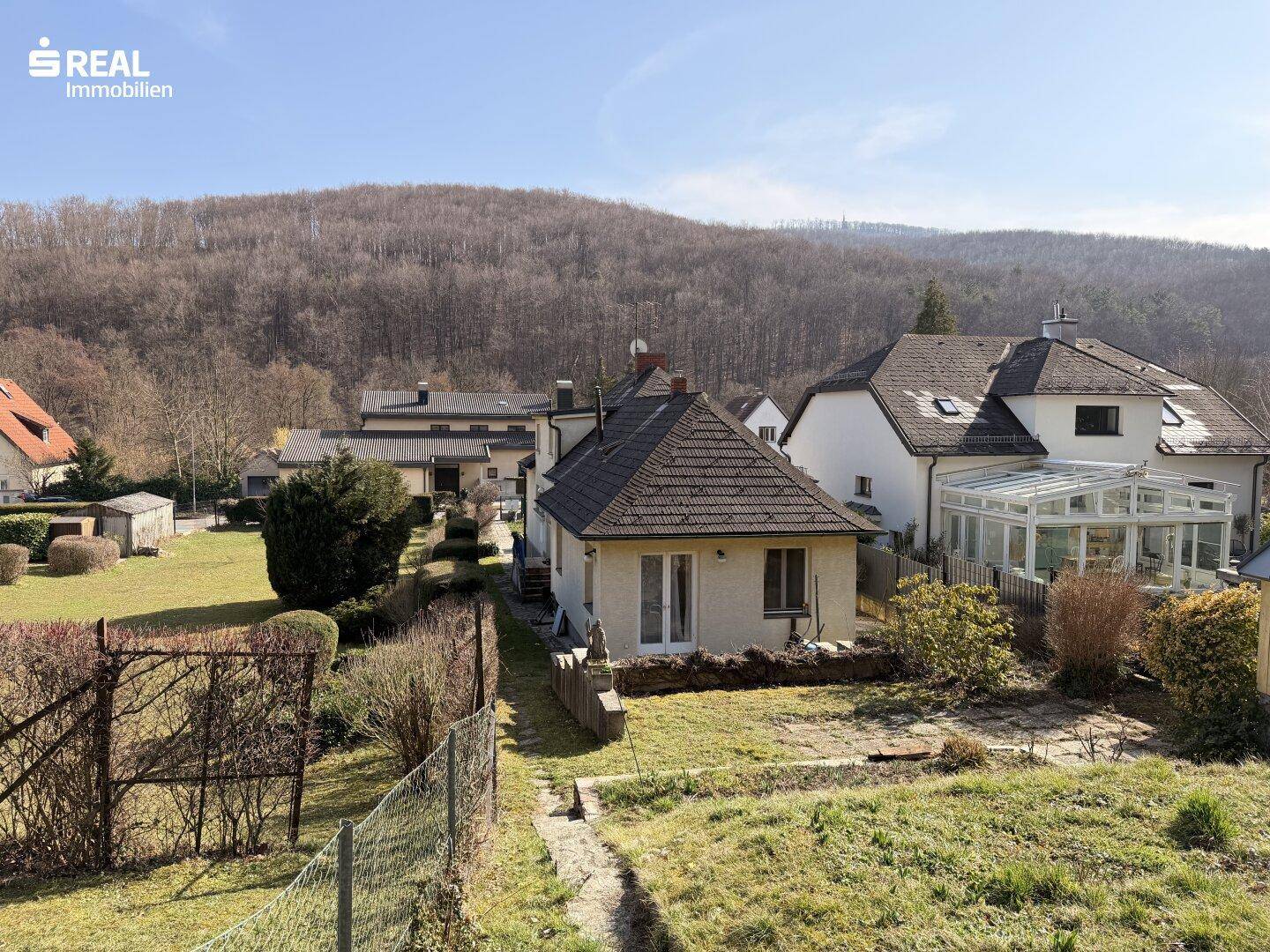 Weitläufiger Blick auf das Haus und die Nachbarschaft mit viel Grün und bewaldeten Hügeln.