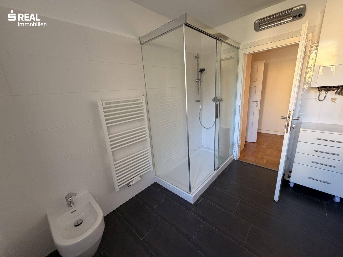 Modernes Badezimmer mit Duschkabine, Bidet und beheiztem Handtuchhalter.