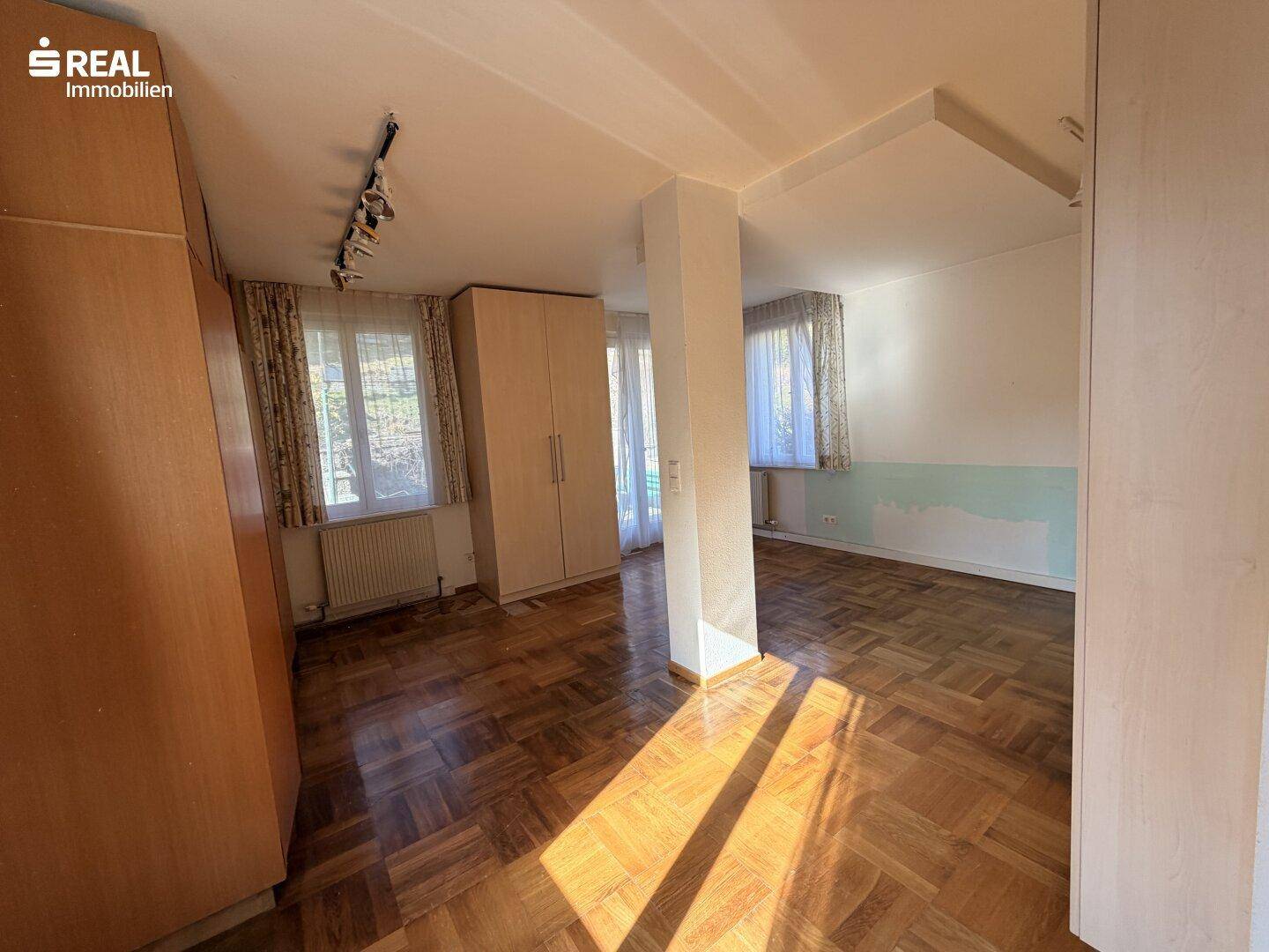 Helles Schlafzimmer mit Fischgrätparkett, Einbauschränken und viel Tageslicht.