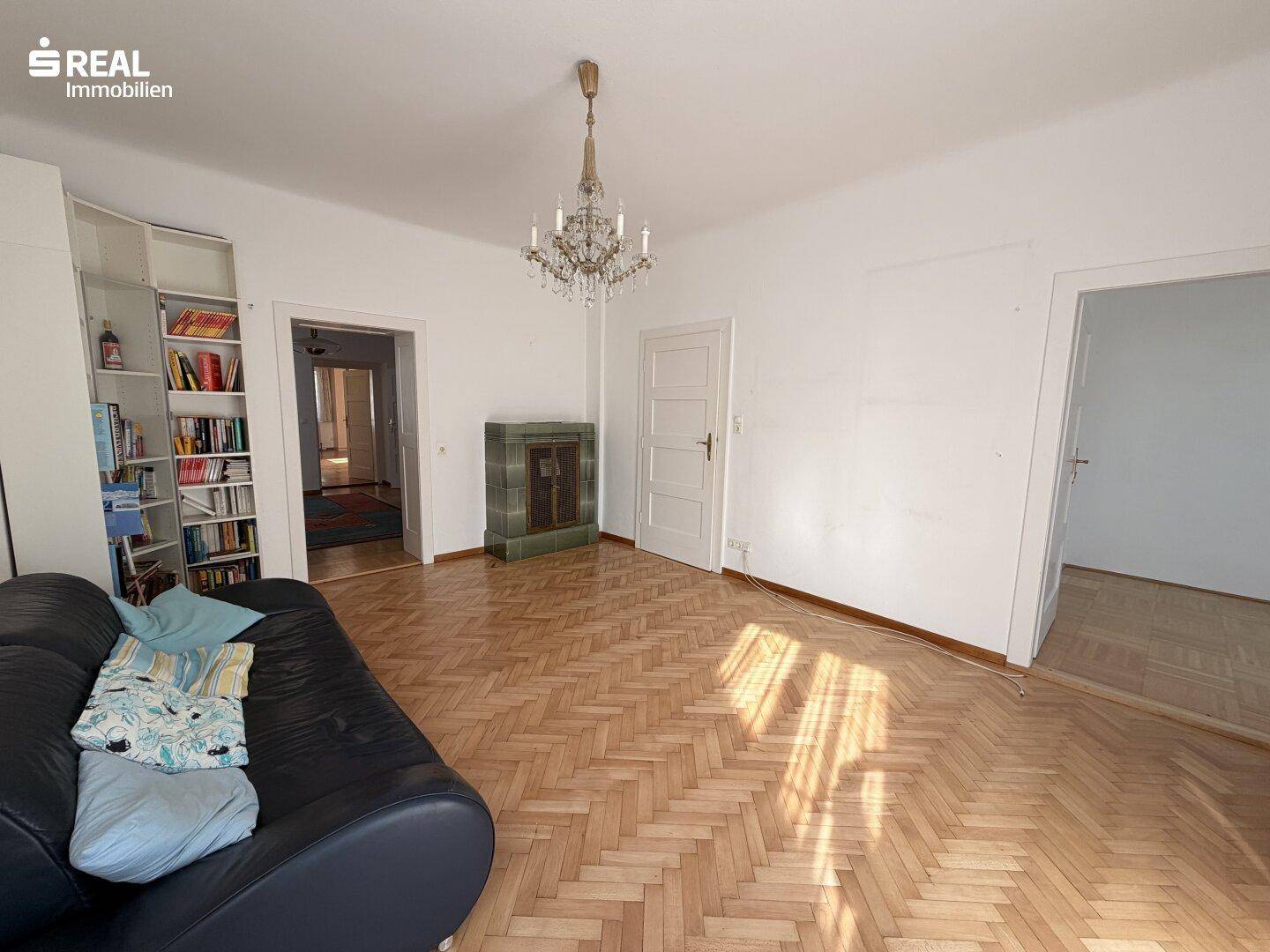 Wohnzimmer mit Fischgrätparkett, Ledersofa und traditionellem Kachelofen.