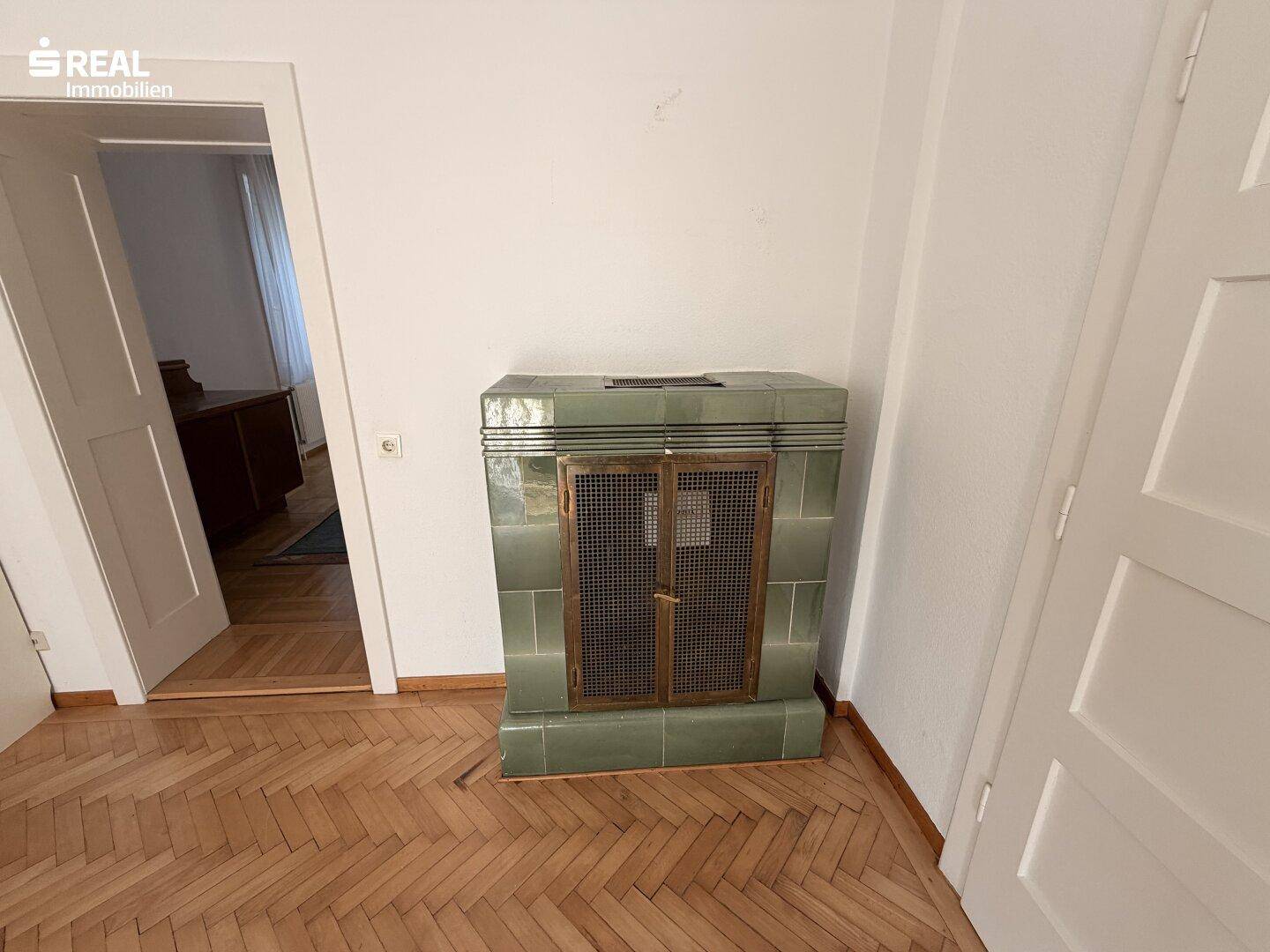Detailansicht eines traditionellen grünen Kachelofens im Wohnzimmer.