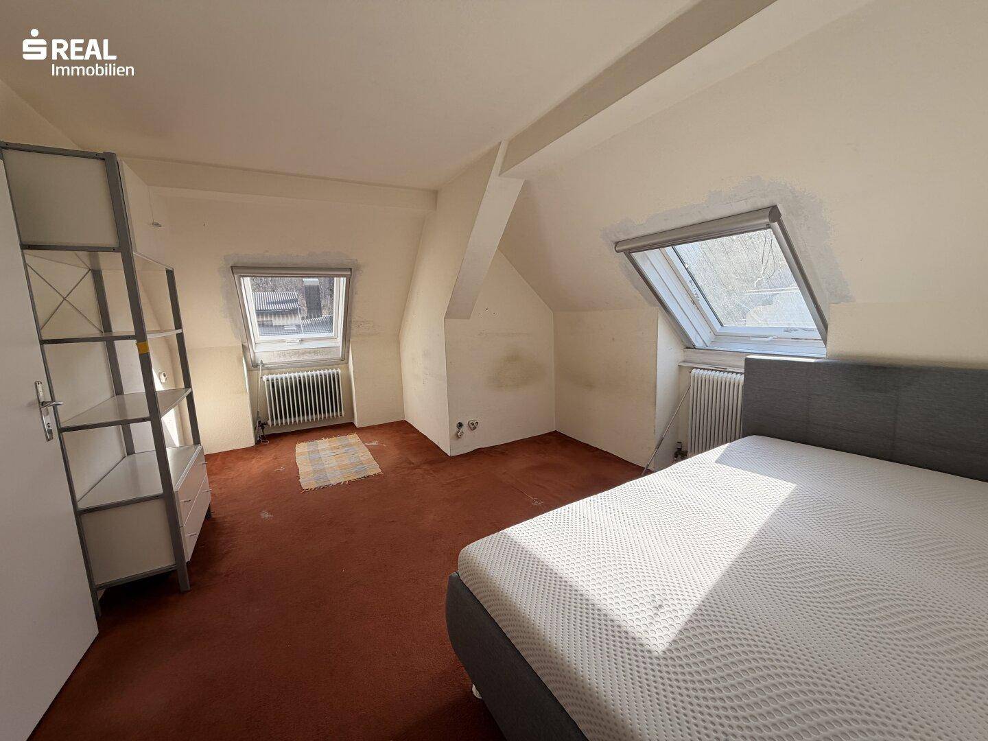 Schlafzimmer im Dachgeschoss mit Dachschrägen, Dachfenstern und Teppichboden.