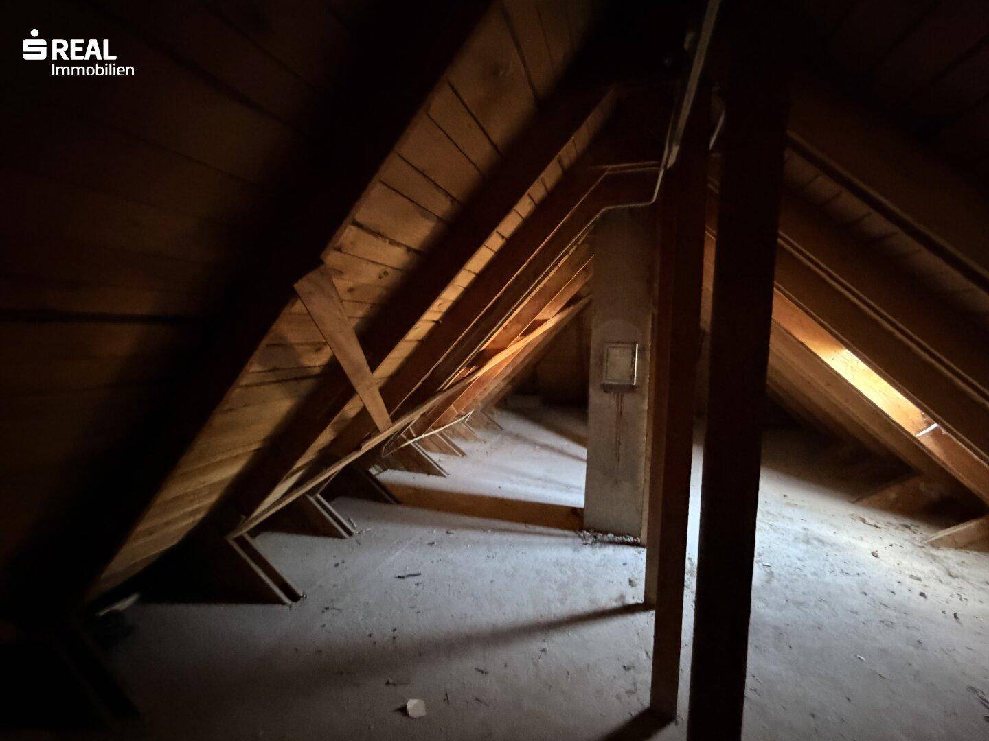 Unausgebauter Dachboden mit sichtbaren Holzbalken und viel Stauraum.
