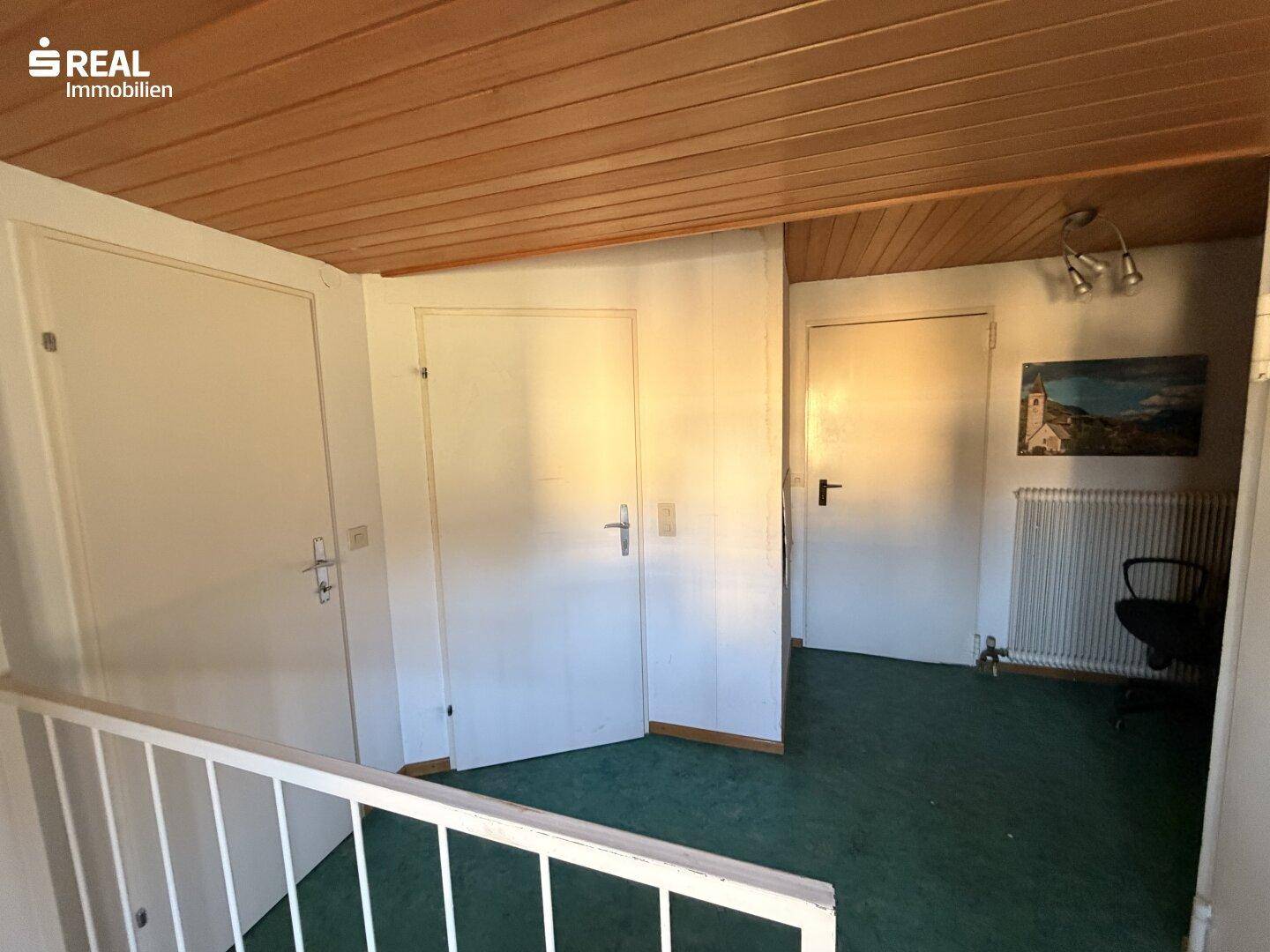 Heller Flurbereich im Dachgeschoss mit Holzdecke und Zugang zu den Zimmern.