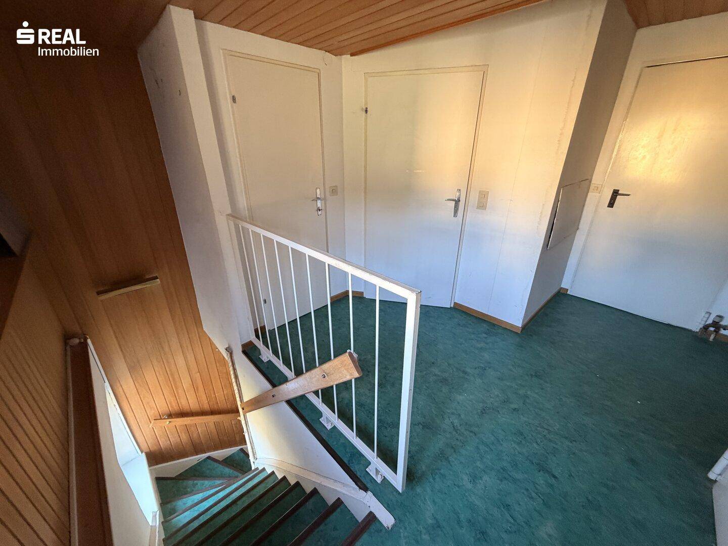 Treppenaufgang zum Dachgeschoss mit Holzverkleidung und Geländer.