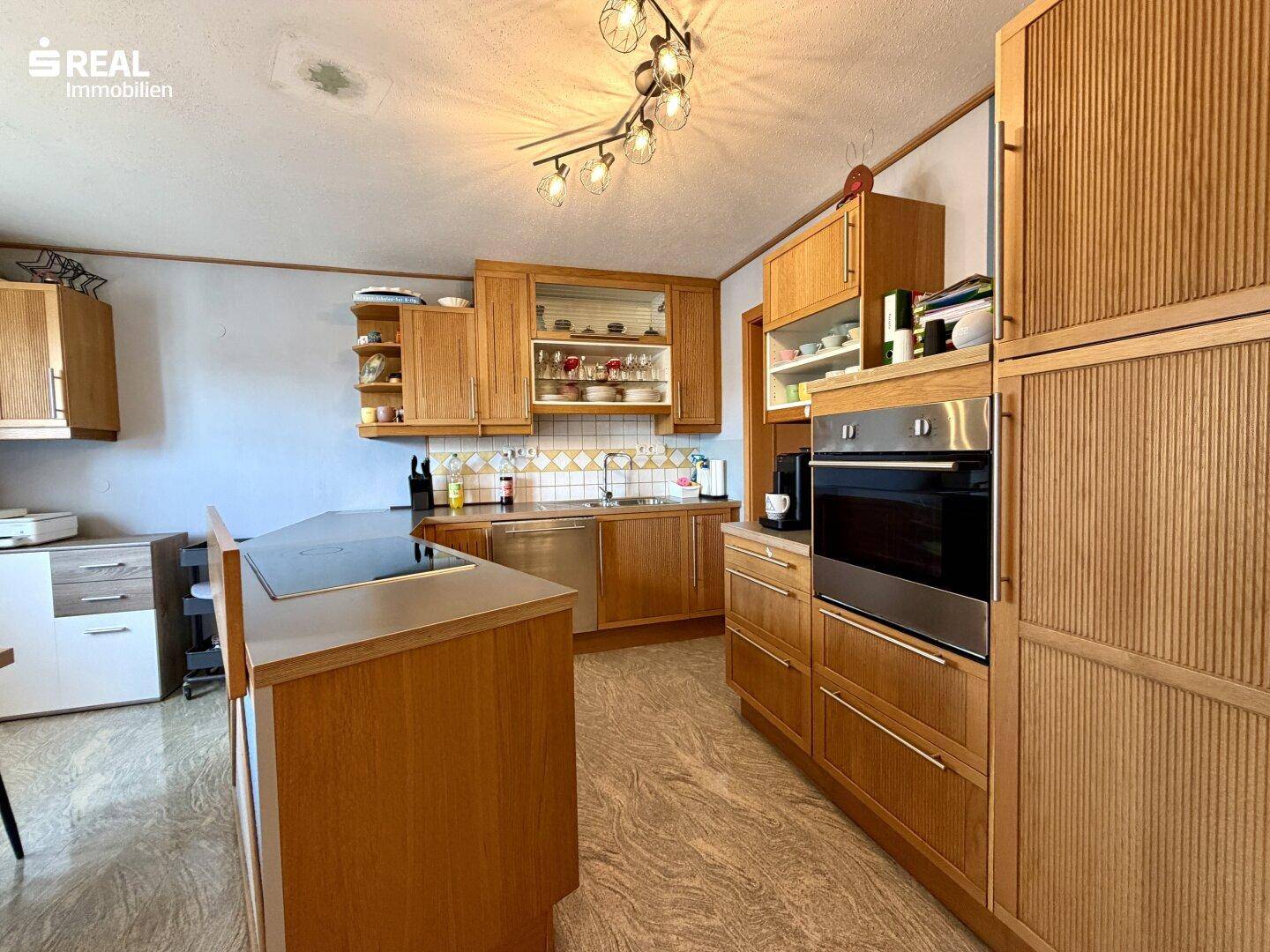 Funktionale Küche mit Holzschränken, integrierten Geräten und Fliesenboden.