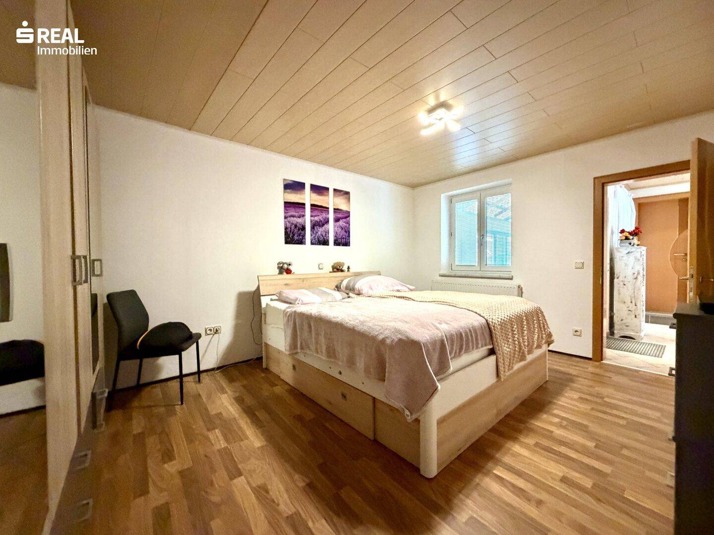 Schlafzimmer mit Doppelbett, Holzdecke und Fenster für natürliches Licht.