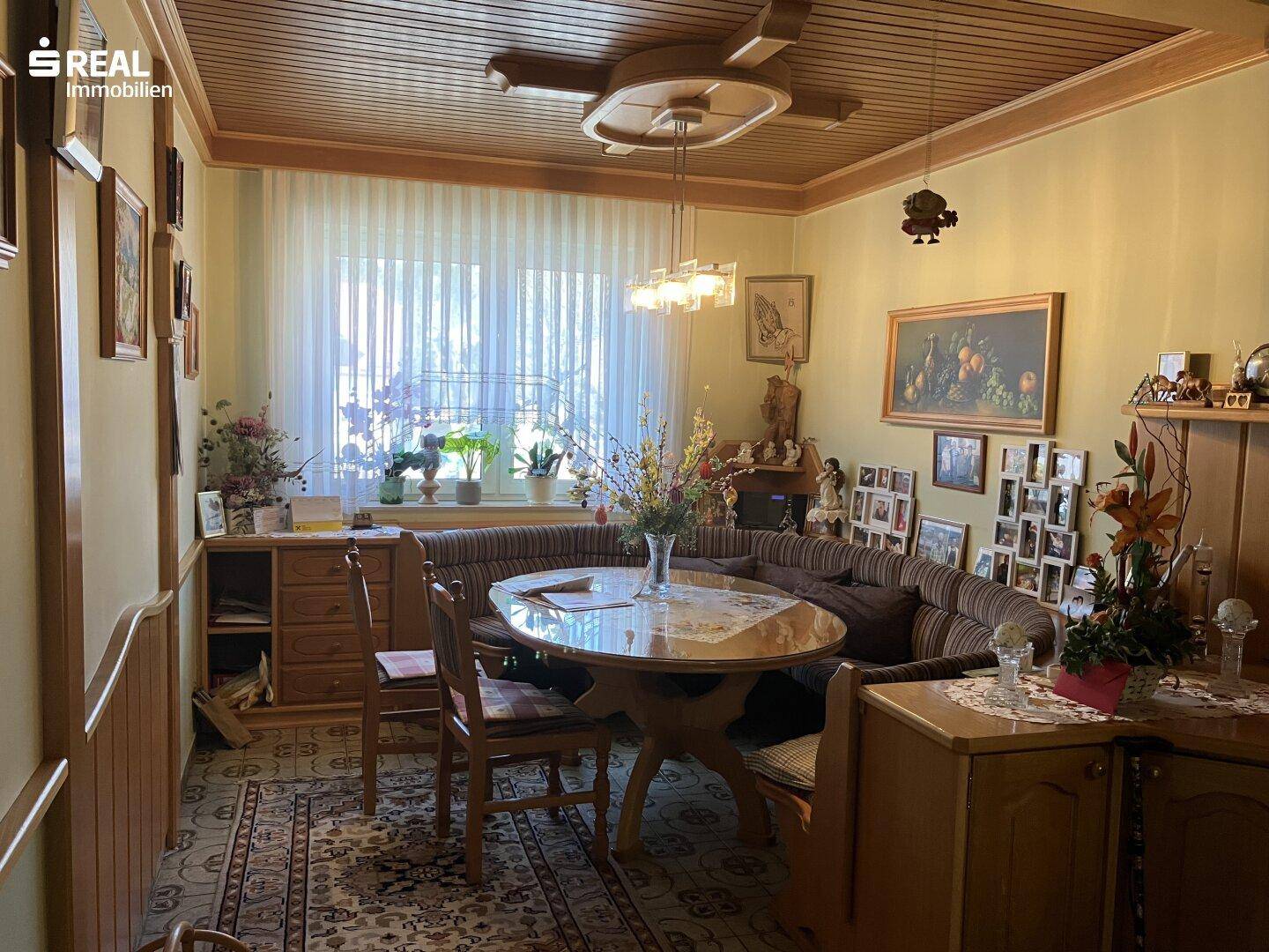 Gemütlicher Wohn-Essbereich mit Holztäfelung, großem Esstisch und traditioneller Einrichtung, ideal für Familien.