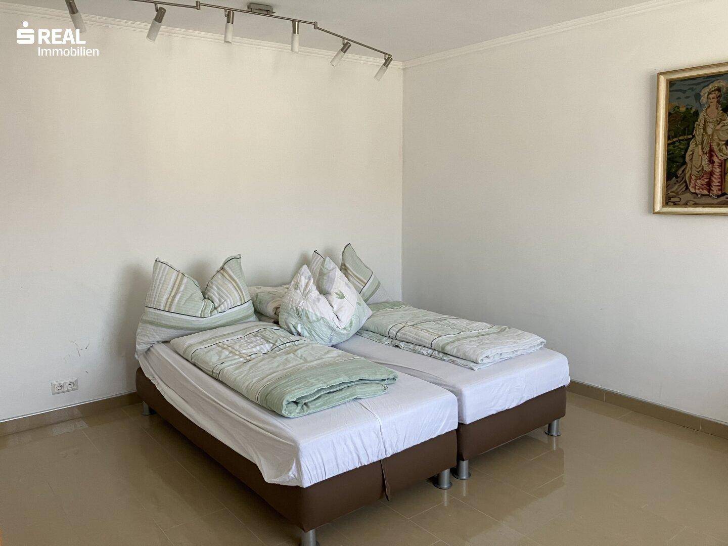 Helles Schlafzimmer mit zwei Einzelbetten, weißen Wänden und glänzendem Fliesenboden, modern und sauber.