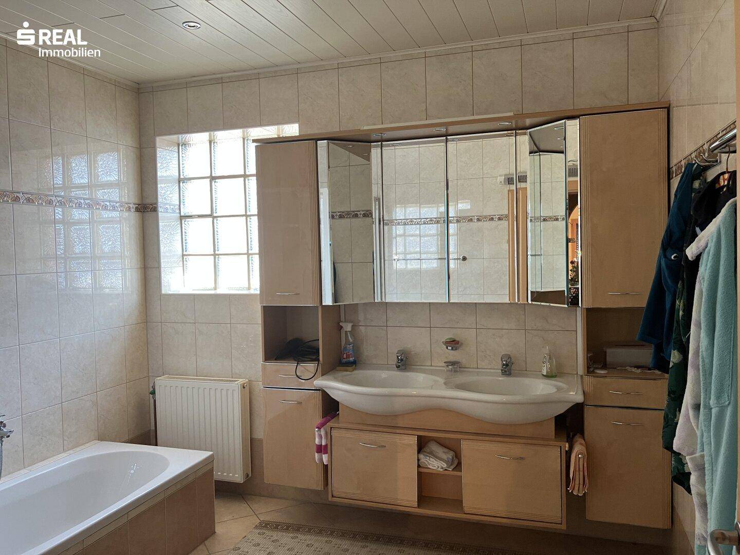Geräumiges Badezimmer mit Badewanne, Doppelwaschbecken und Spiegelschrank, bietet Komfort und Stauraum.