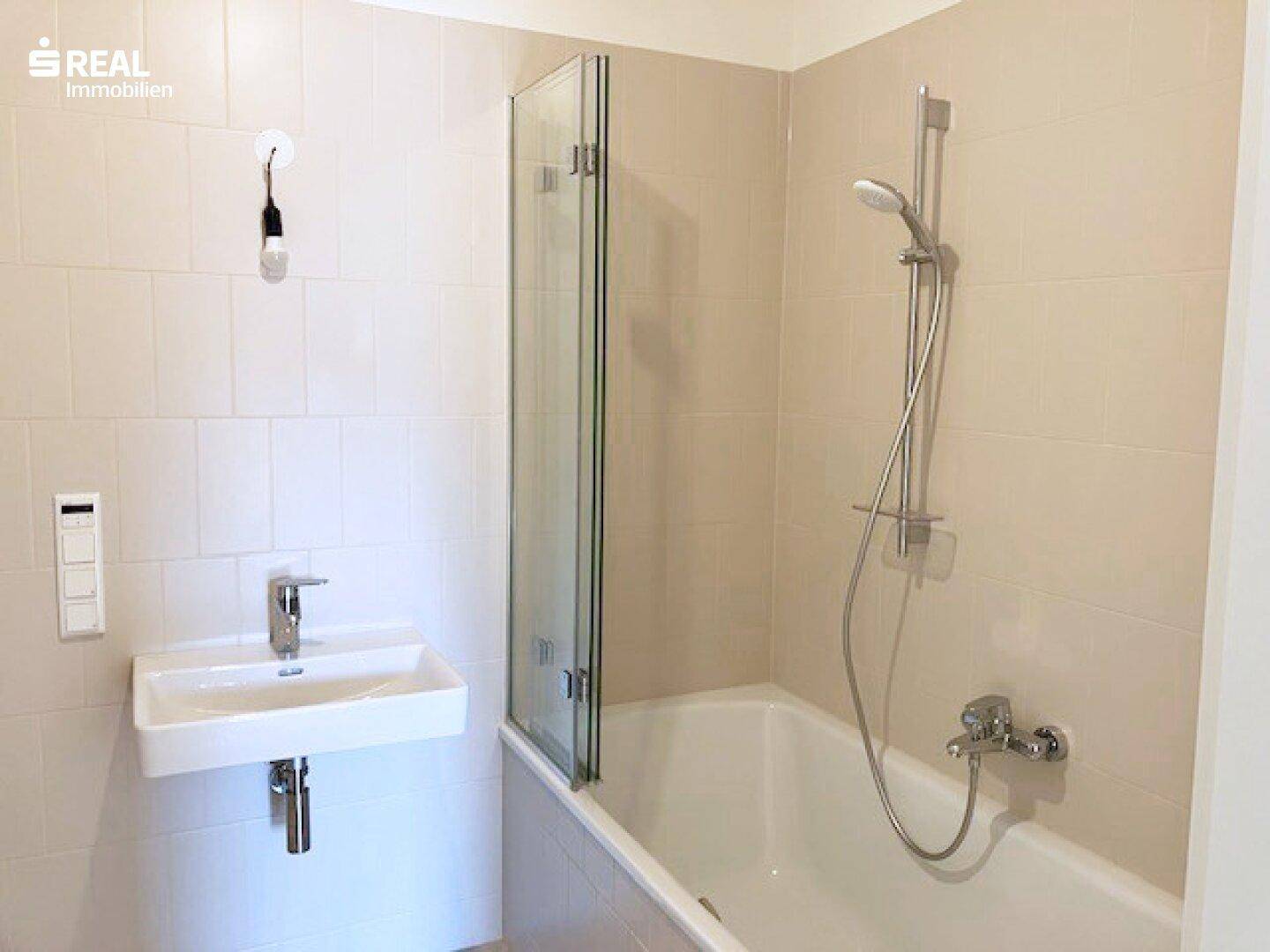 Modernes Badezimmer mit Badewanne, Dusche und beigefarbenen Fliesen.
