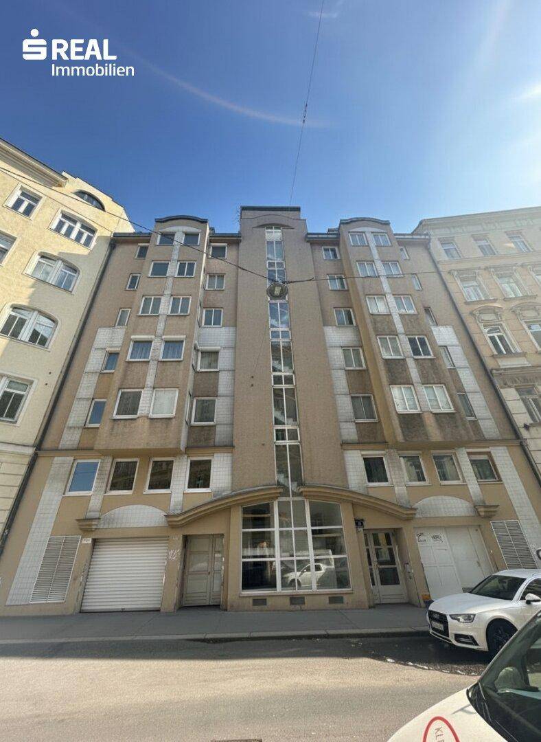 Fassade eines Mehrfamilienhauses mit mehreren Etagen und Fenstern zur Straße hin.