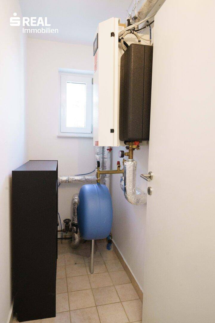 Hauswirtschaftsraum mit Heizungsanlage, Rohren und einem kleinen Fenster.