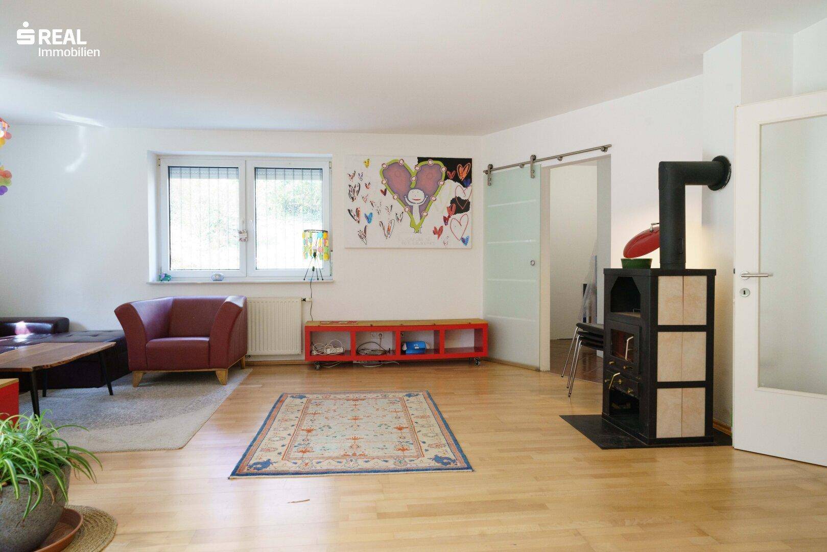 Wohnzimmer mit Kaminofen, Holzboden und bunten Dekorationselementen.