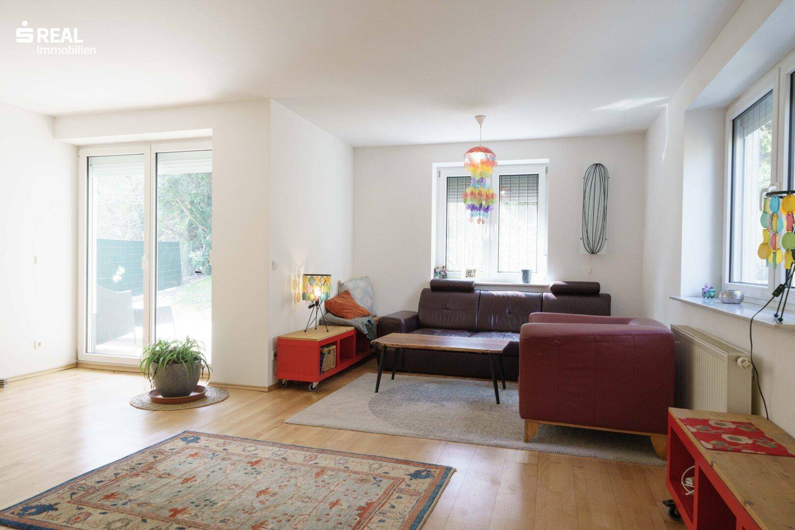 Wohnzimmer mit direktem Zugang zum Garten, Holzboden und viel Tageslicht.