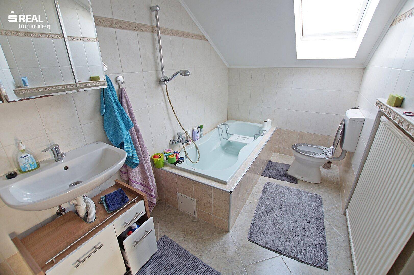 Badezimmer im Dachgeschoss mit Badewanne, Waschbecken und Dachfenster.