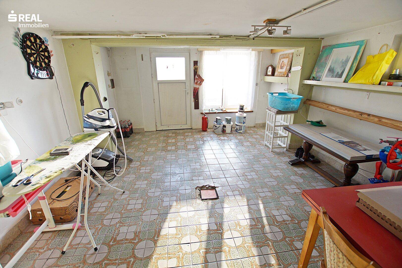 Geräumiger Kellerraum mit Fliesenboden, Fenster und verschiedenen Haushaltsgeräten.