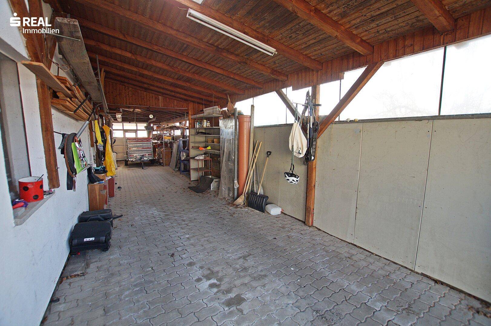 Große Garage mit Holzdachkonstruktion und gepflastertem Boden.