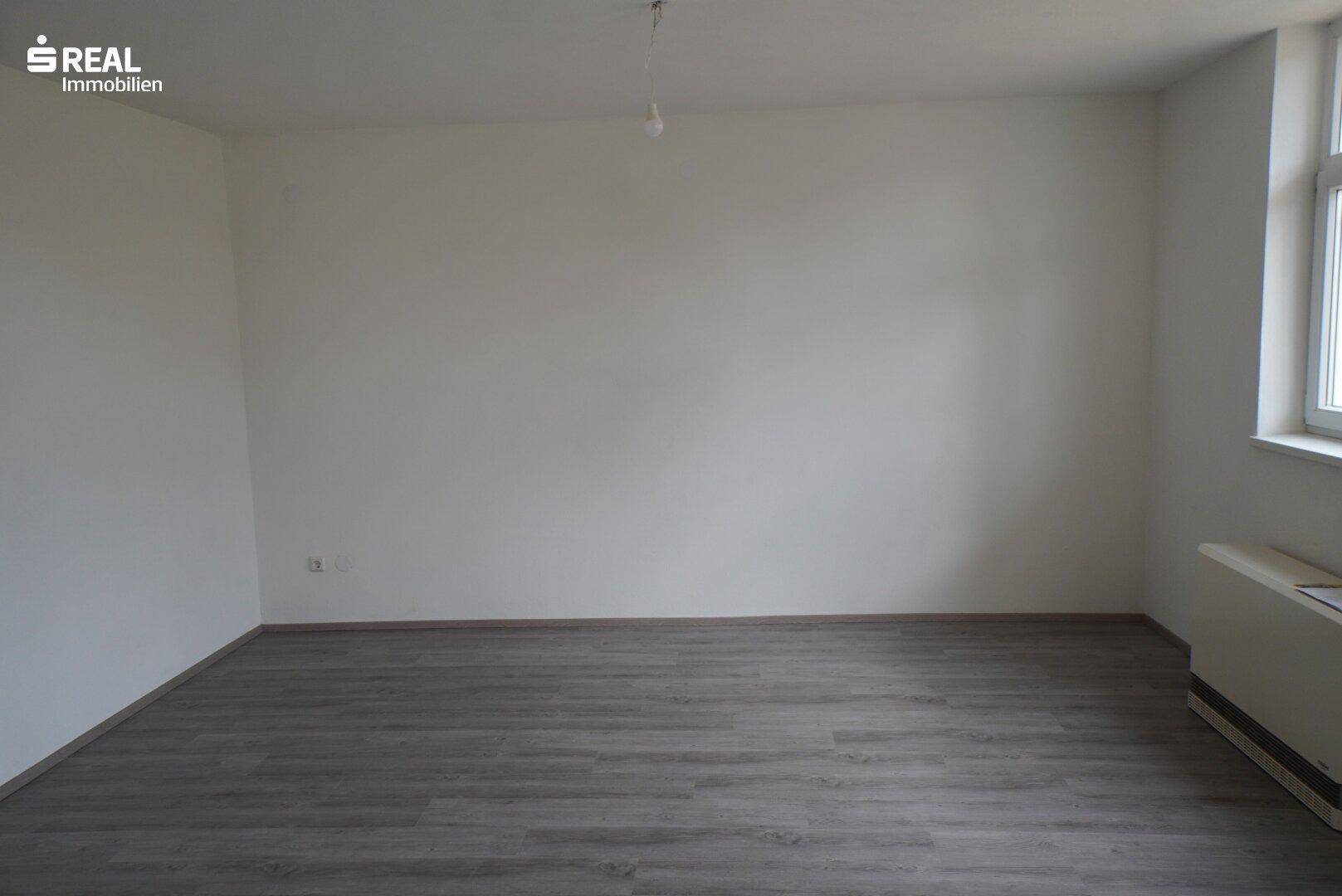 Helles Wohnzimmer mit Laminatboden und viel Platz für individuelle Einrichtung.