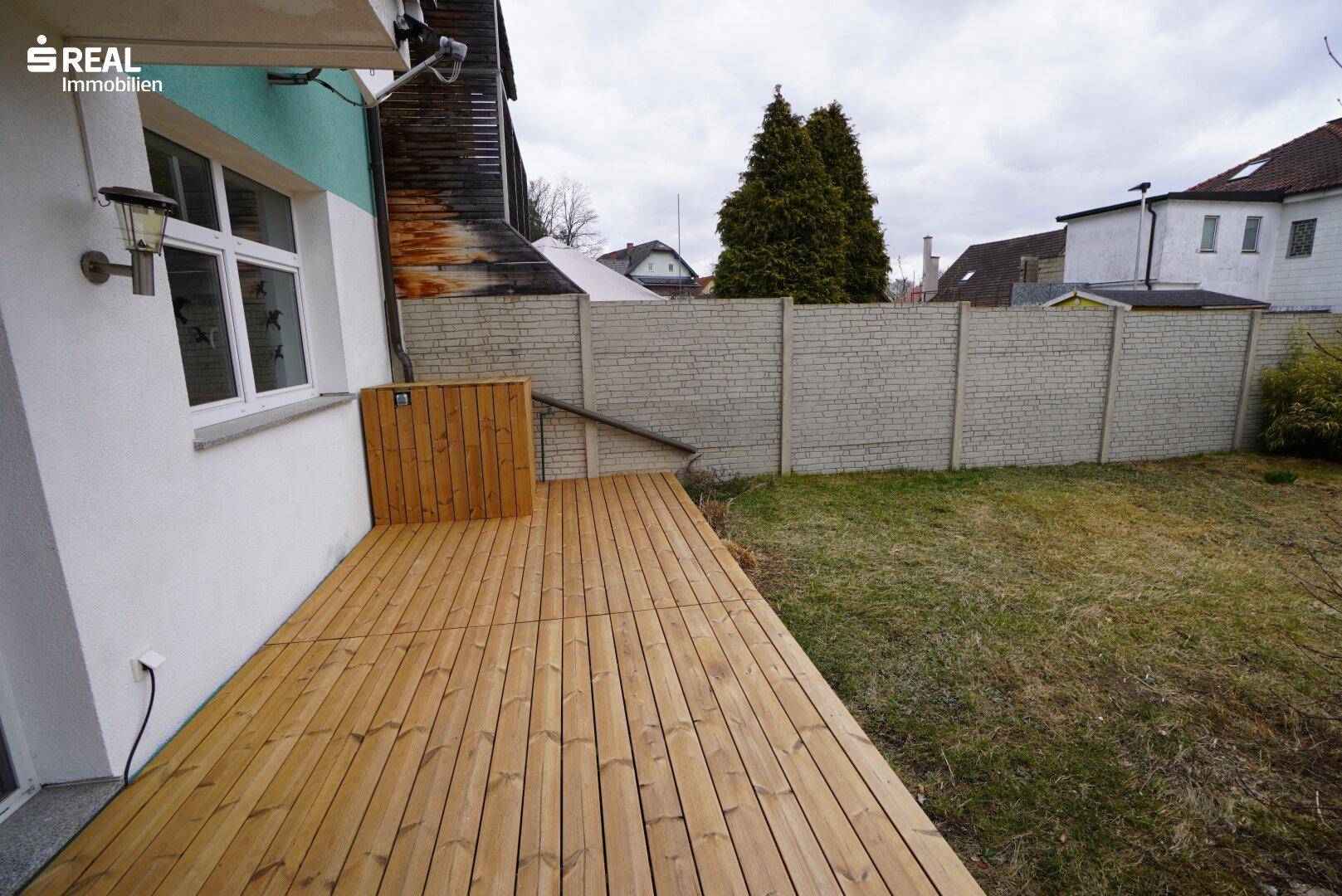 Geräumige Holzterrasse mit Blick auf den Garten und die Umgebung.
