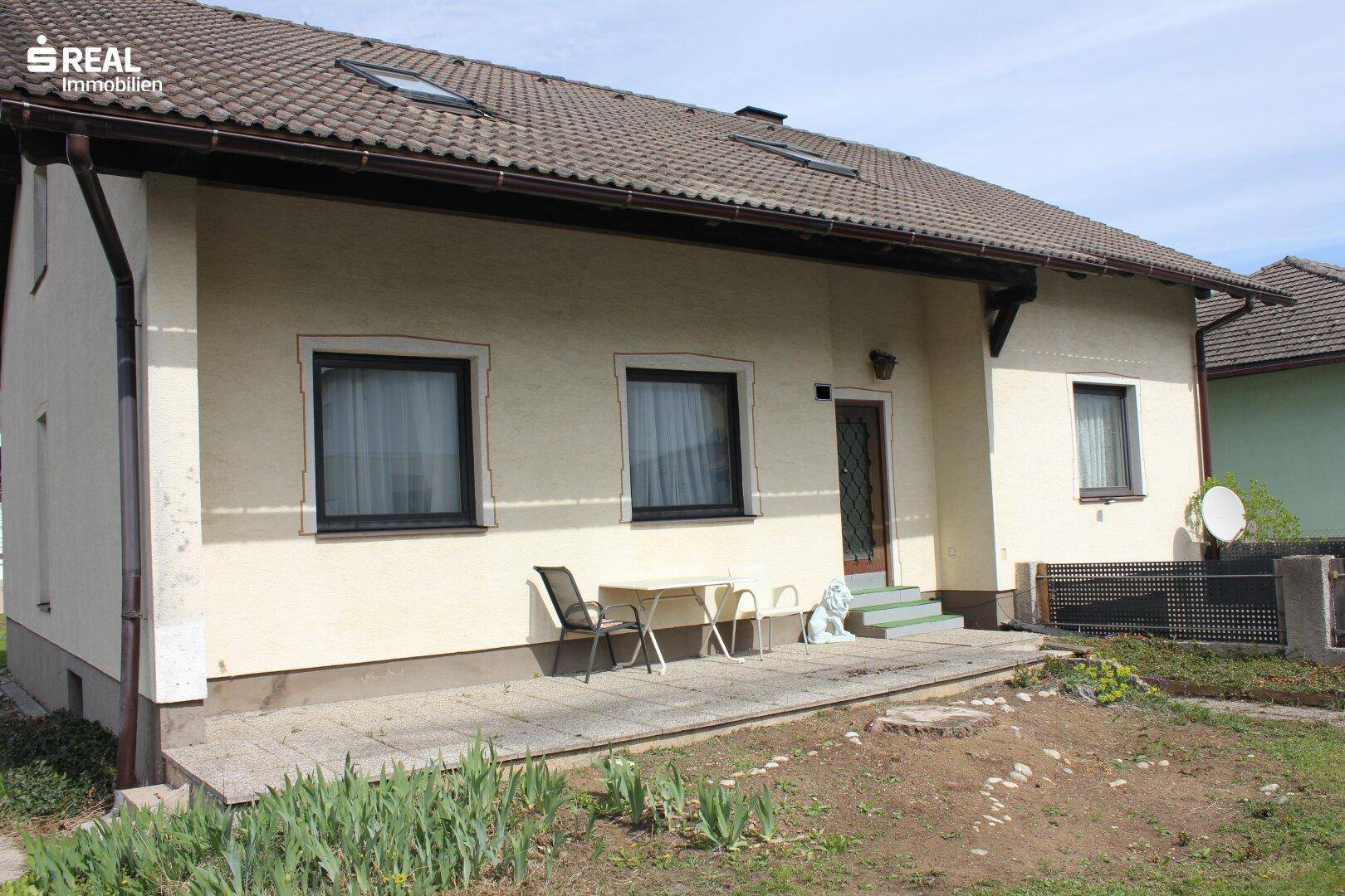 Kleine gepflasterte Terrasse an der Seite des Hauses mit Sitzgelegenheiten im Freien.