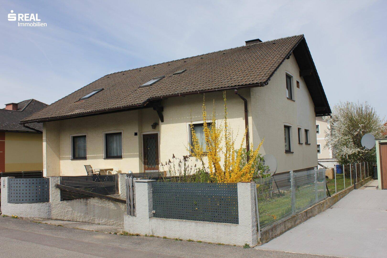 Seitenansicht des Einfamilienhauses mit Gartenbereich und Zufahrt zum Grundstück.