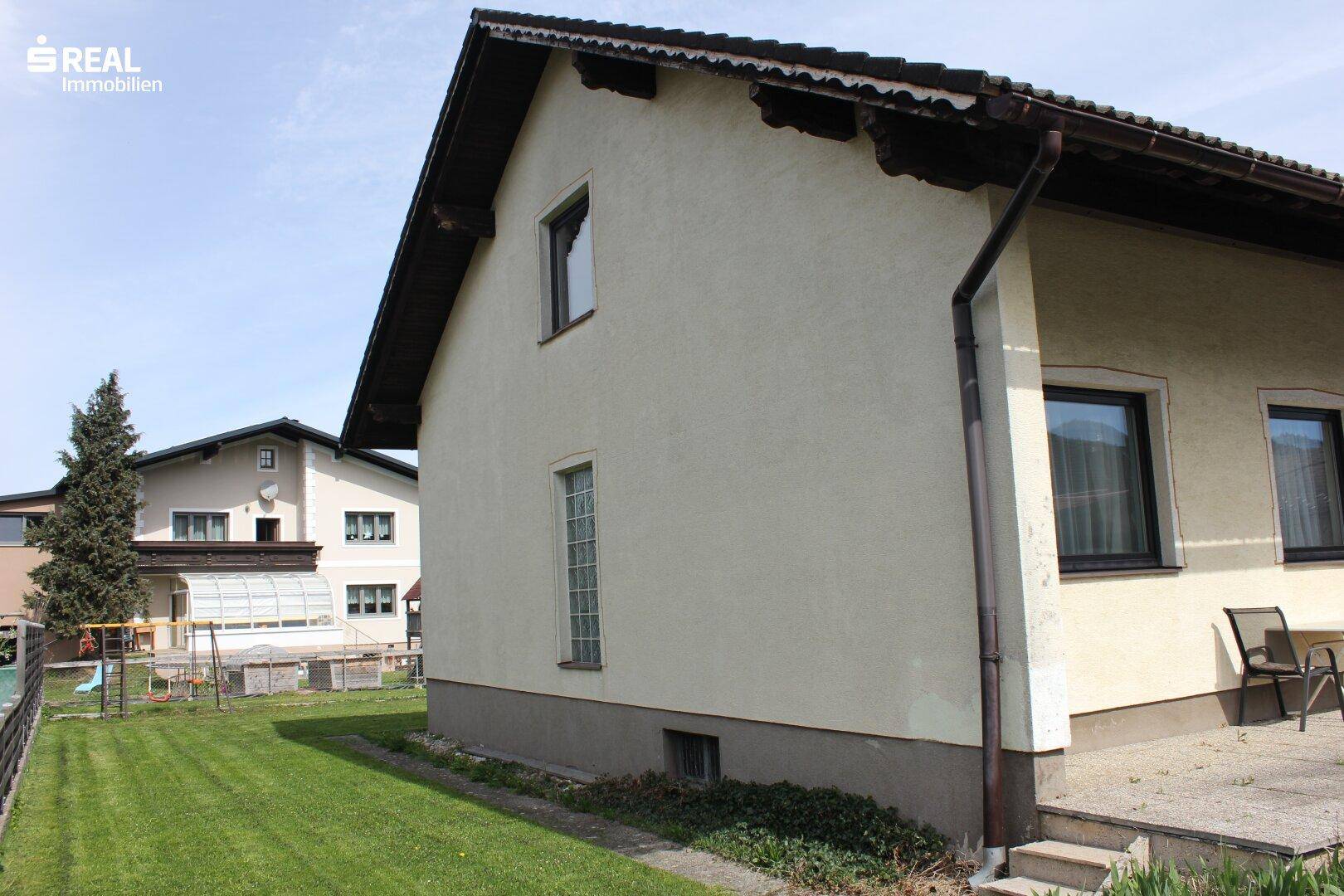 Seitenansicht des Hauses mit großem Rasenbereich und angrenzendem Nachbargrundstück.