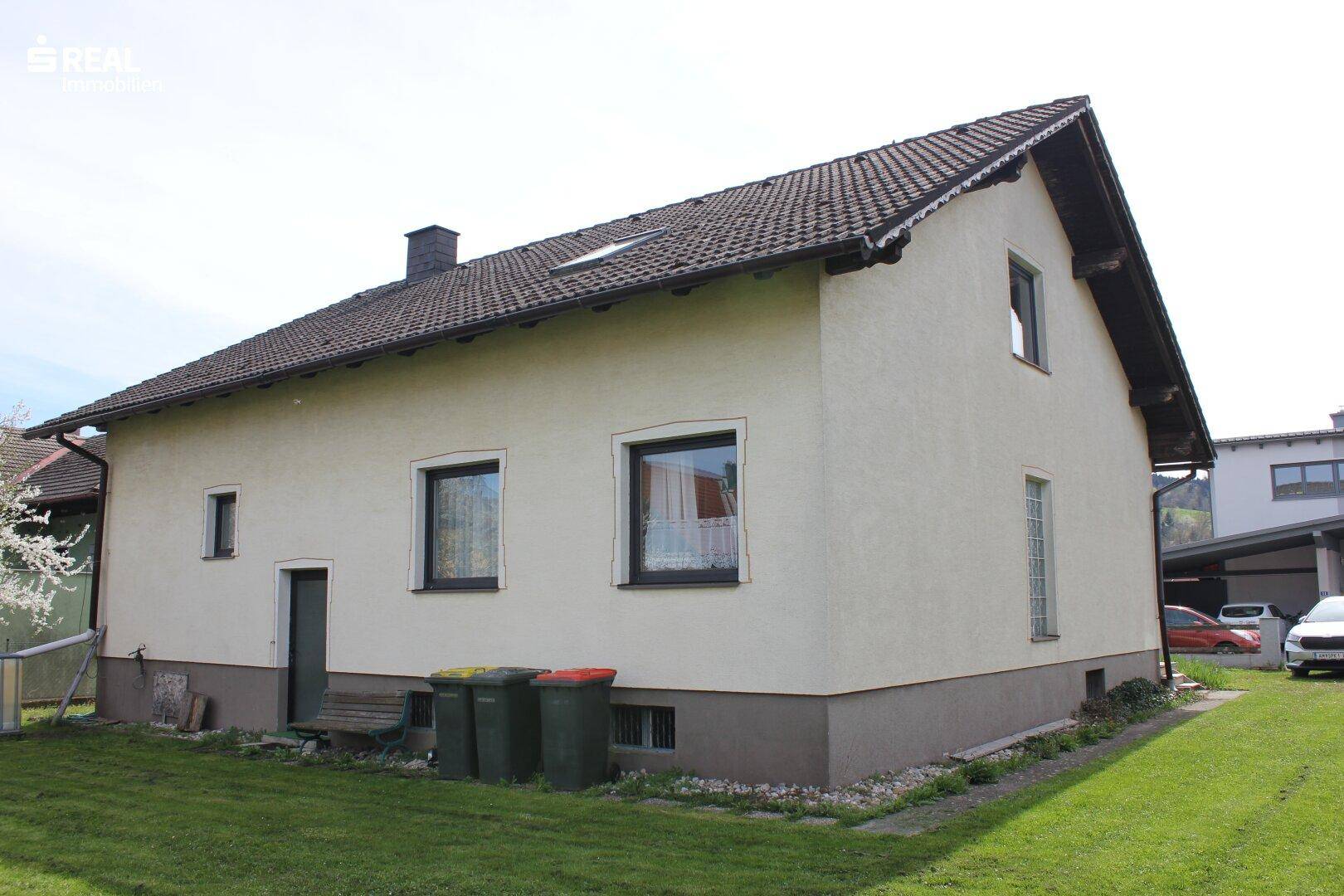 Rückseite des Hauses mit Rasenfläche, Fenstern und Zugang zum Garten.