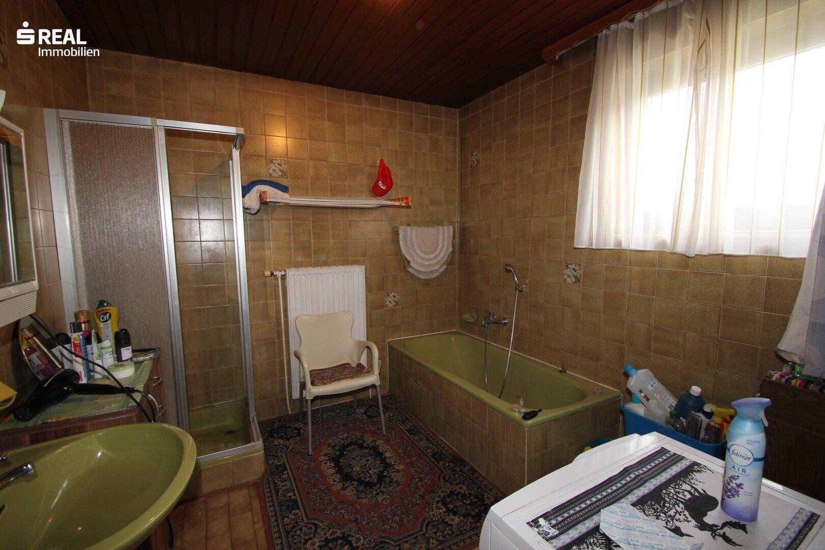 Badezimmer im Stil der 80er Jahre mit braunen Fliesen, Badewanne und Duschkabine.