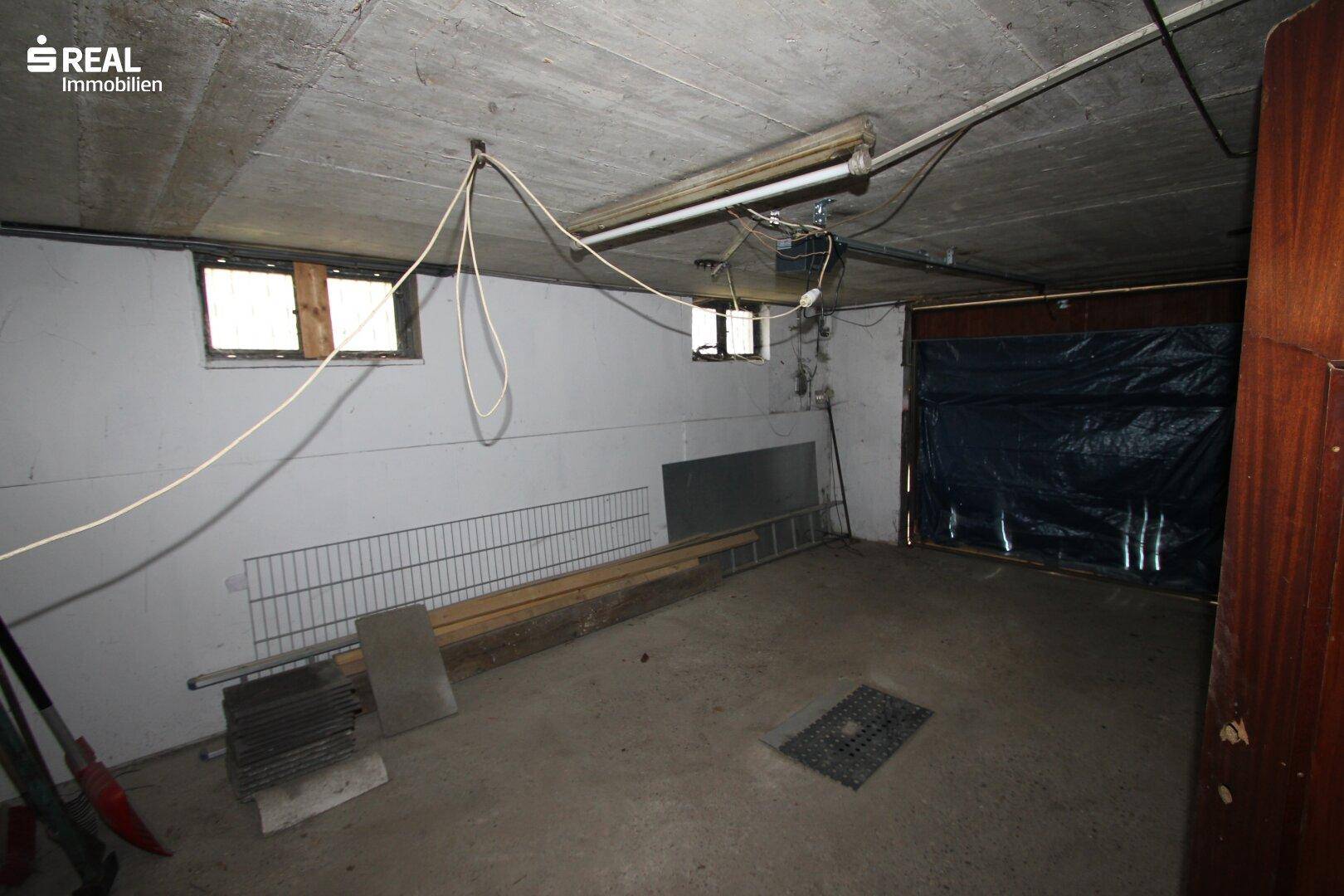 Geräumiger Kellerraum mit Betonwänden, kleinen Fenstern und einfacher Beleuchtung, vielseitig nutzbar.
