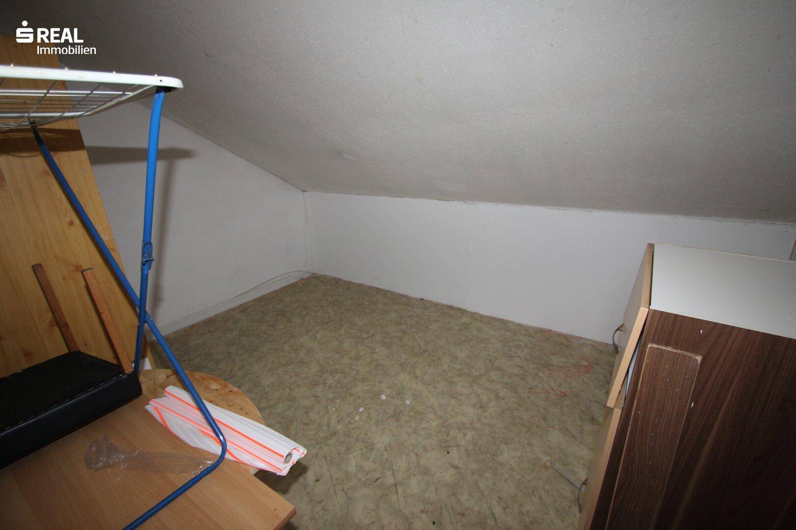Dachbodenraum mit schräger Decke und einfacher Ausstattung, ideal als Abstellraum oder Lagerfläche.