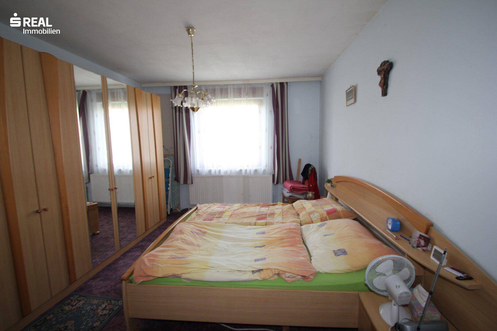 Schlafzimmer mit Doppelbett, Spiegelschränken und einem Fenster mit Blick nach draußen.