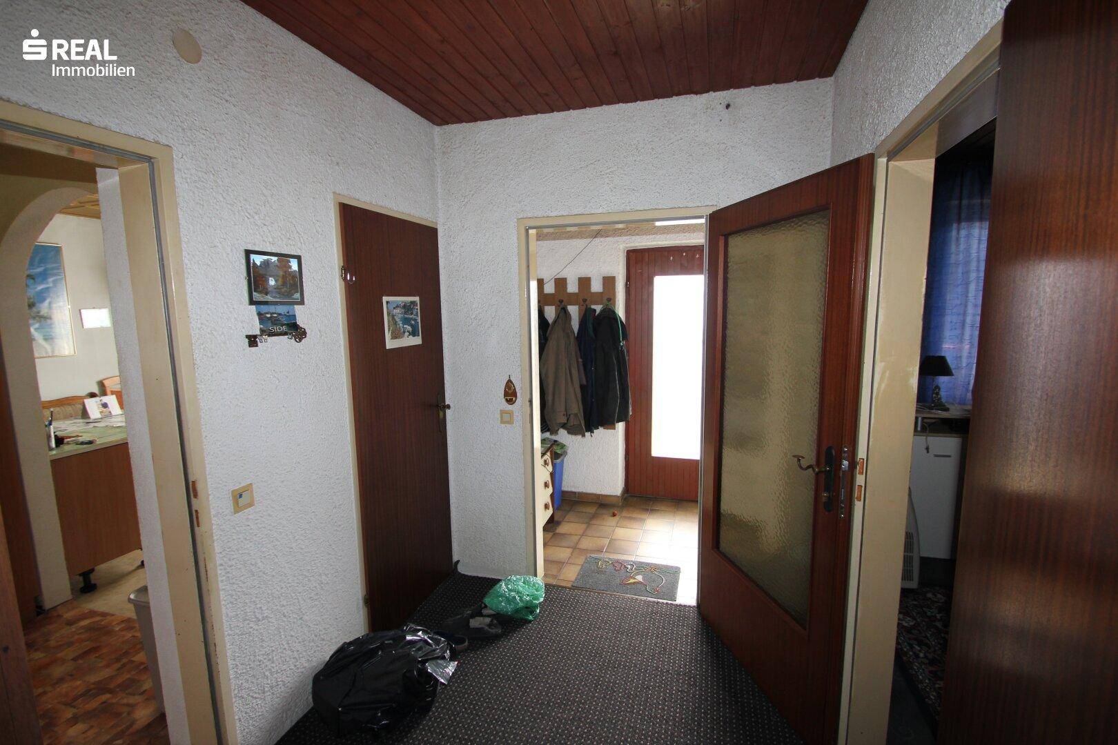 Flur mit mehreren Türen, Garderobe und Zugang zu verschiedenen Räumen.