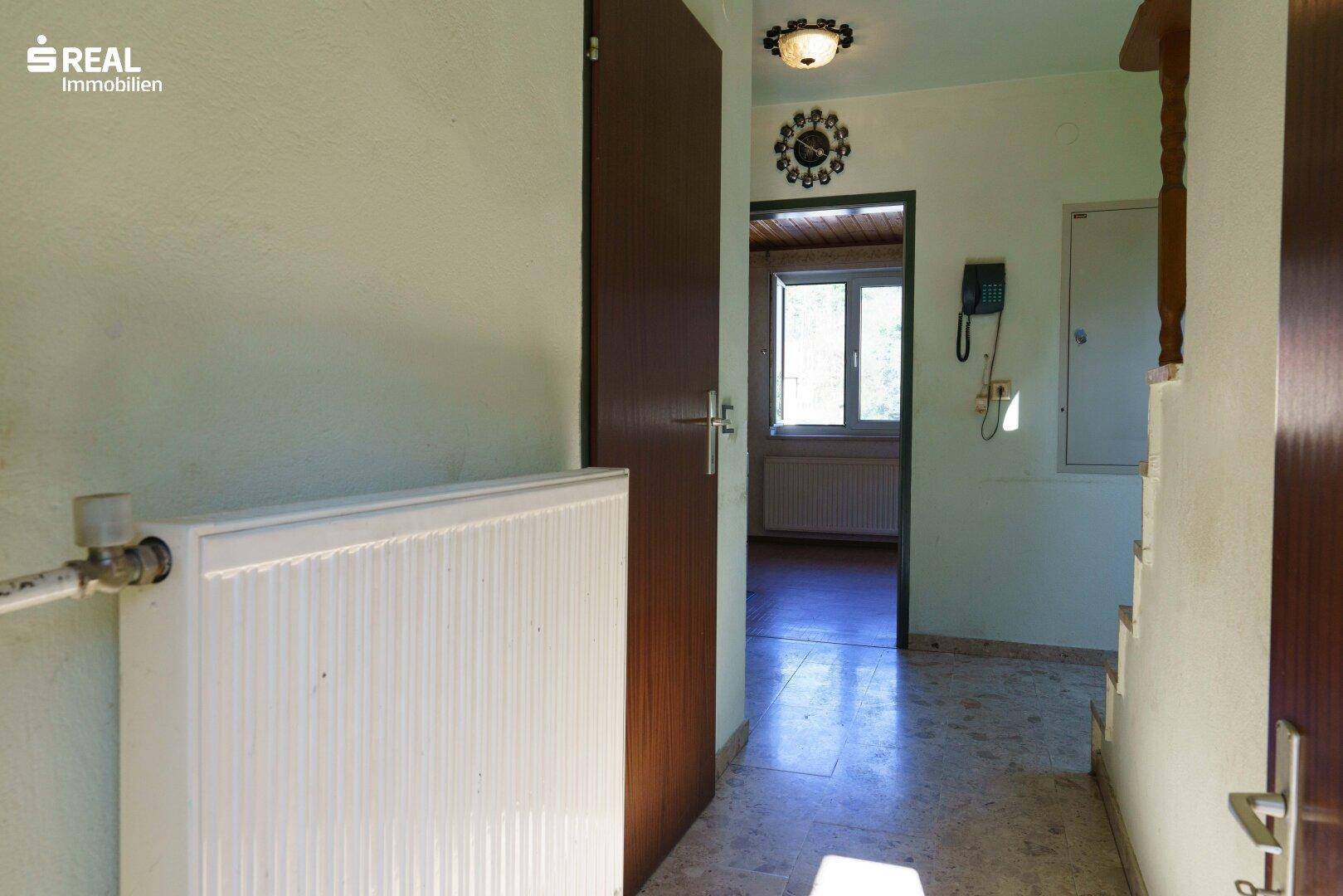 Eingangsbereich mit Fliesenboden, Heizkörper und Türen zu angrenzenden Räumen.