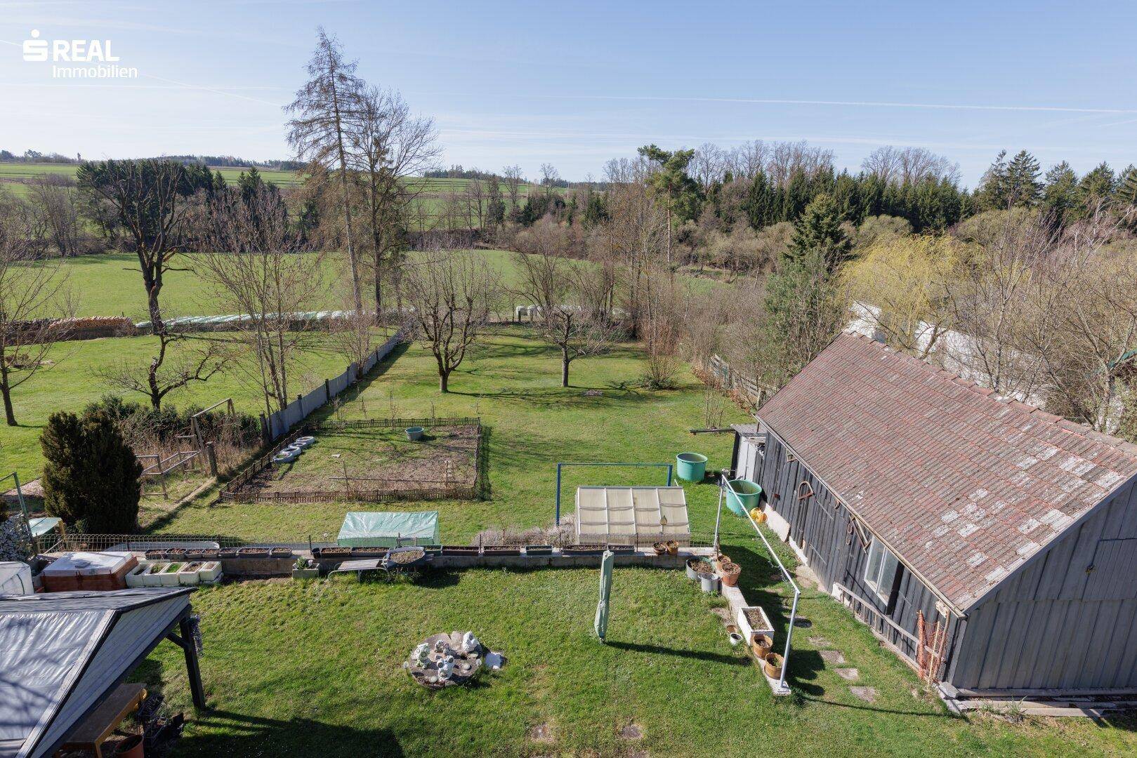 Großer Garten mit Rasenfläche, Obstbäumen und Blick auf die ländliche Umgebung.