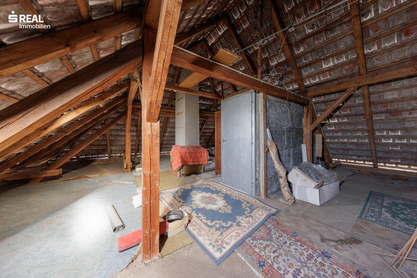 Geräumiger Dachboden mit sichtbaren Holzbalken und Stauraum.