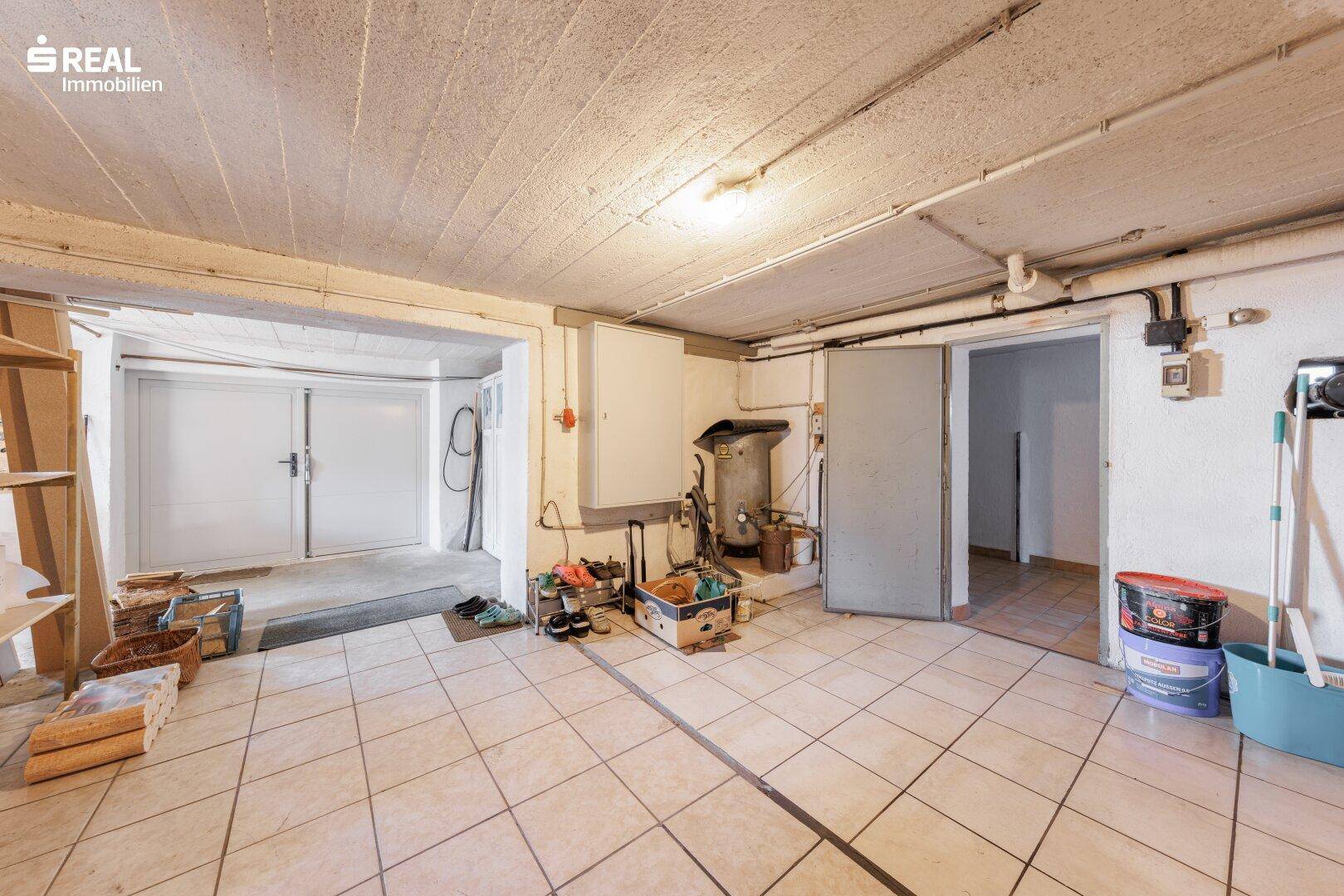 Kellerraum mit Fliesenboden, Lagerflächen und Zugang zur Garage.