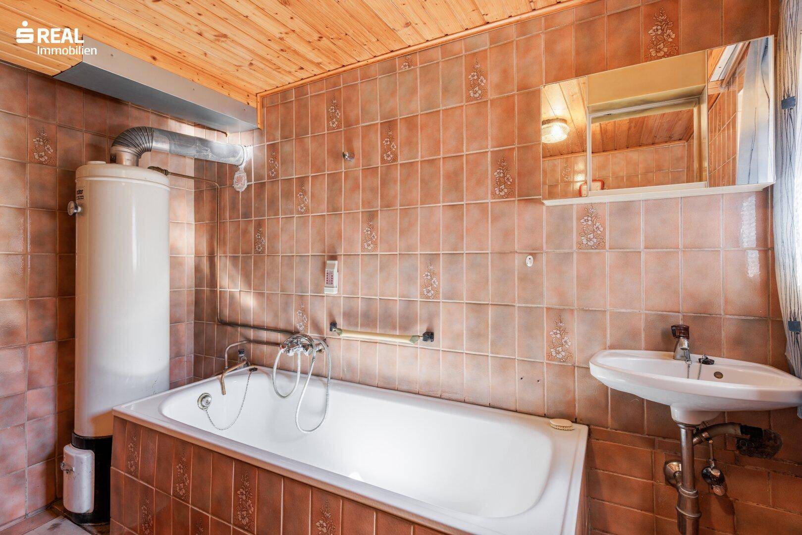 Rustikales Badezimmer mit Badewanne, Waschbecken und braunen Fliesen.