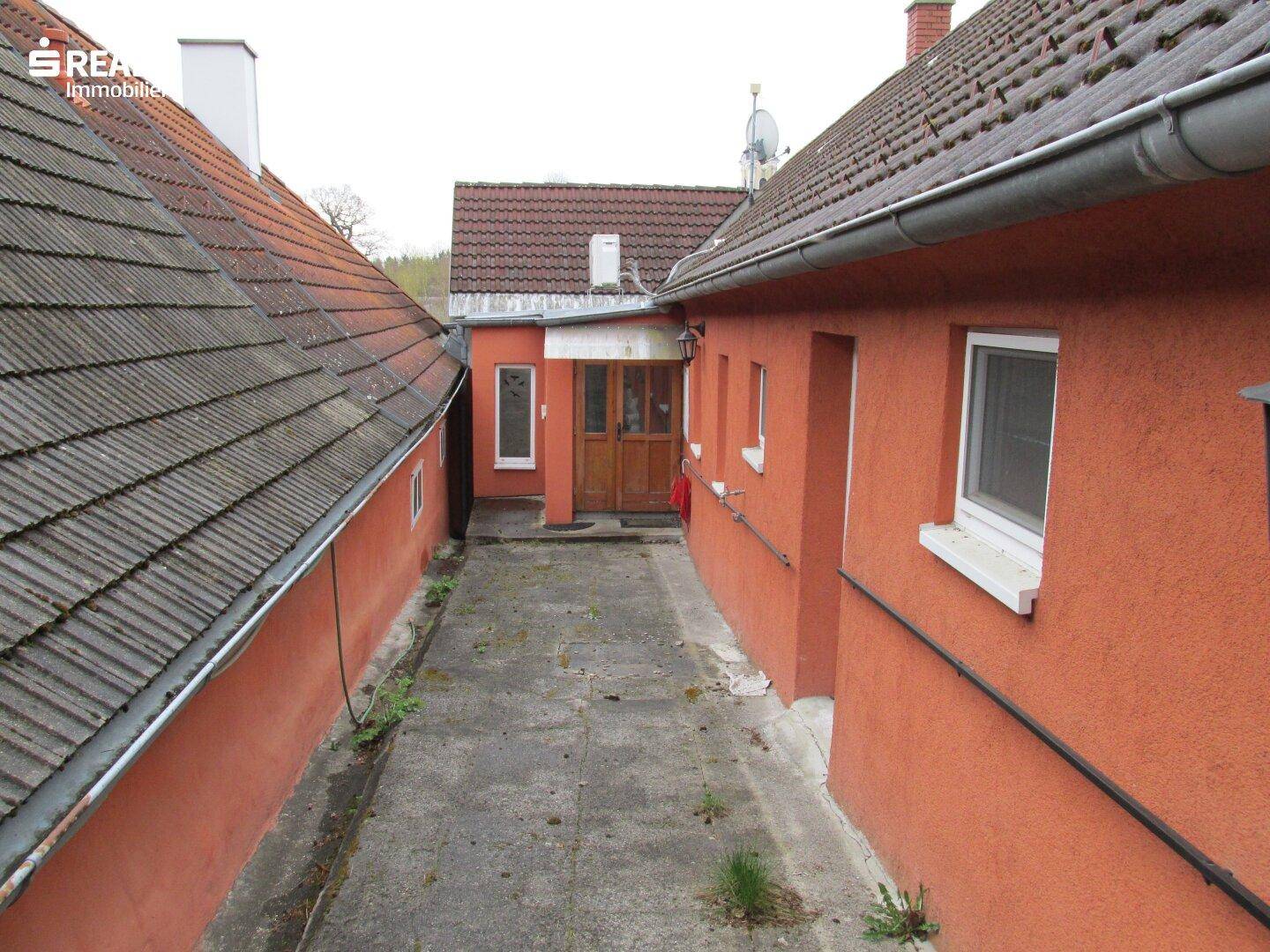 Schmaler gepflasterter Weg zwischen zwei Gebäuden, der zum Hinterhof führt.