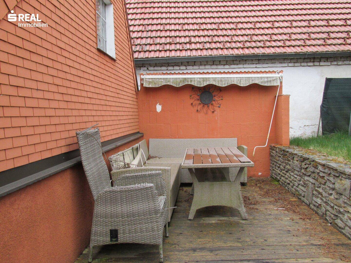 Holzterrasse mit Gartenmöbeln und Markise, ideal für entspannte Stunden im Freien.