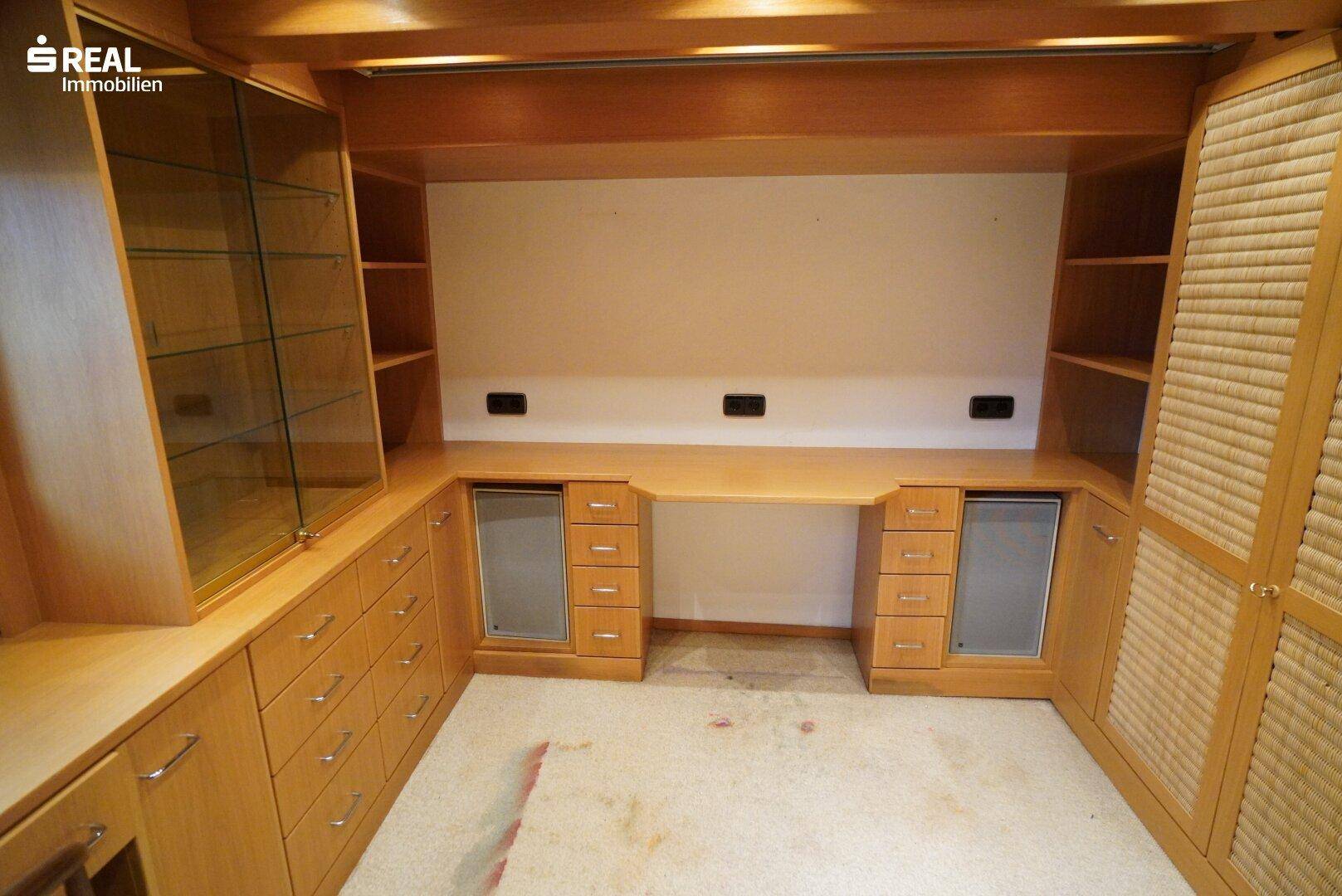 Arbeitszimmer mit integriertem Schreibtischbereich und vielen Holzschränken.