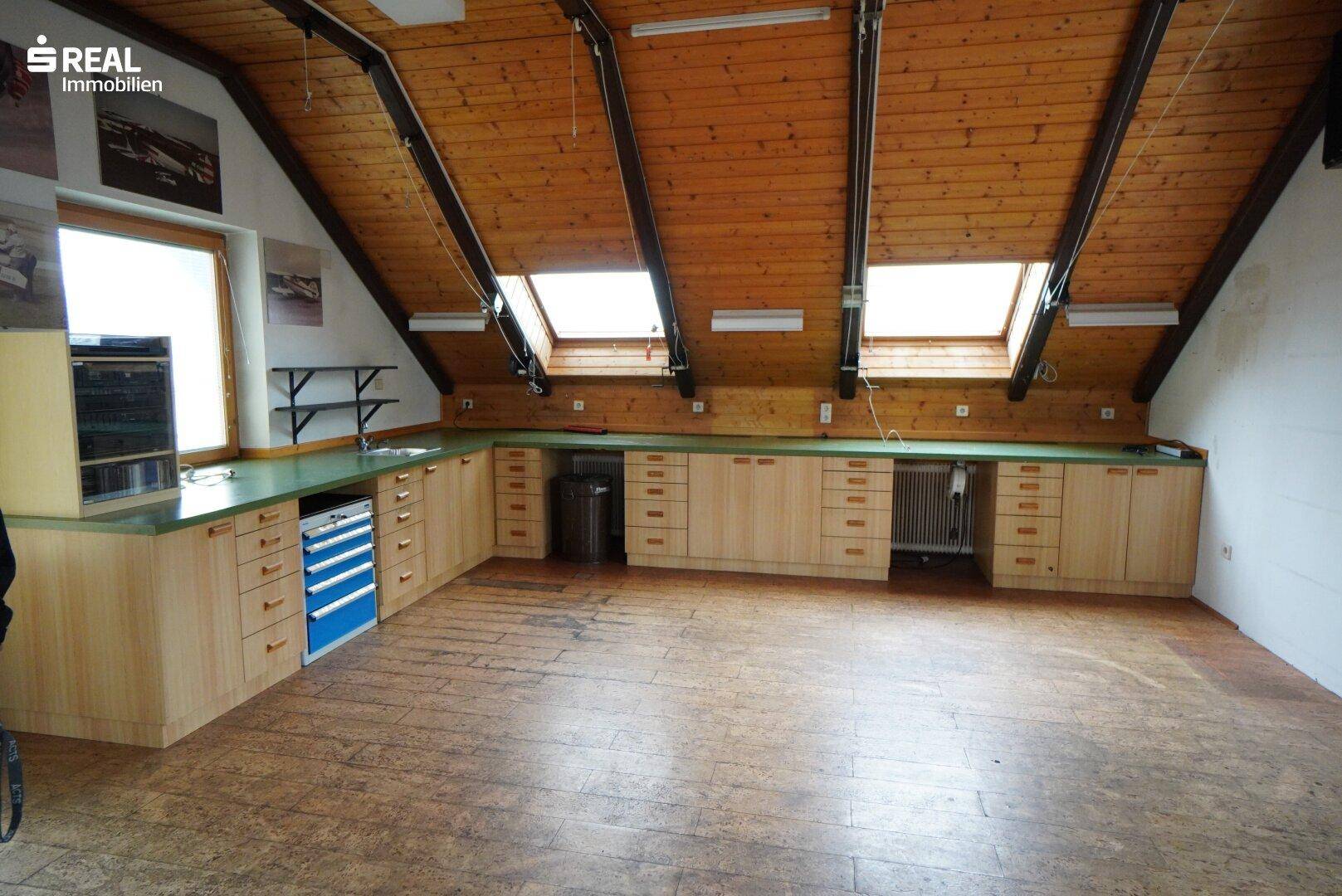 Weiterer Blick in den großen Dachbodenraum mit Arbeitsbereich, Spüle und Stauraum.