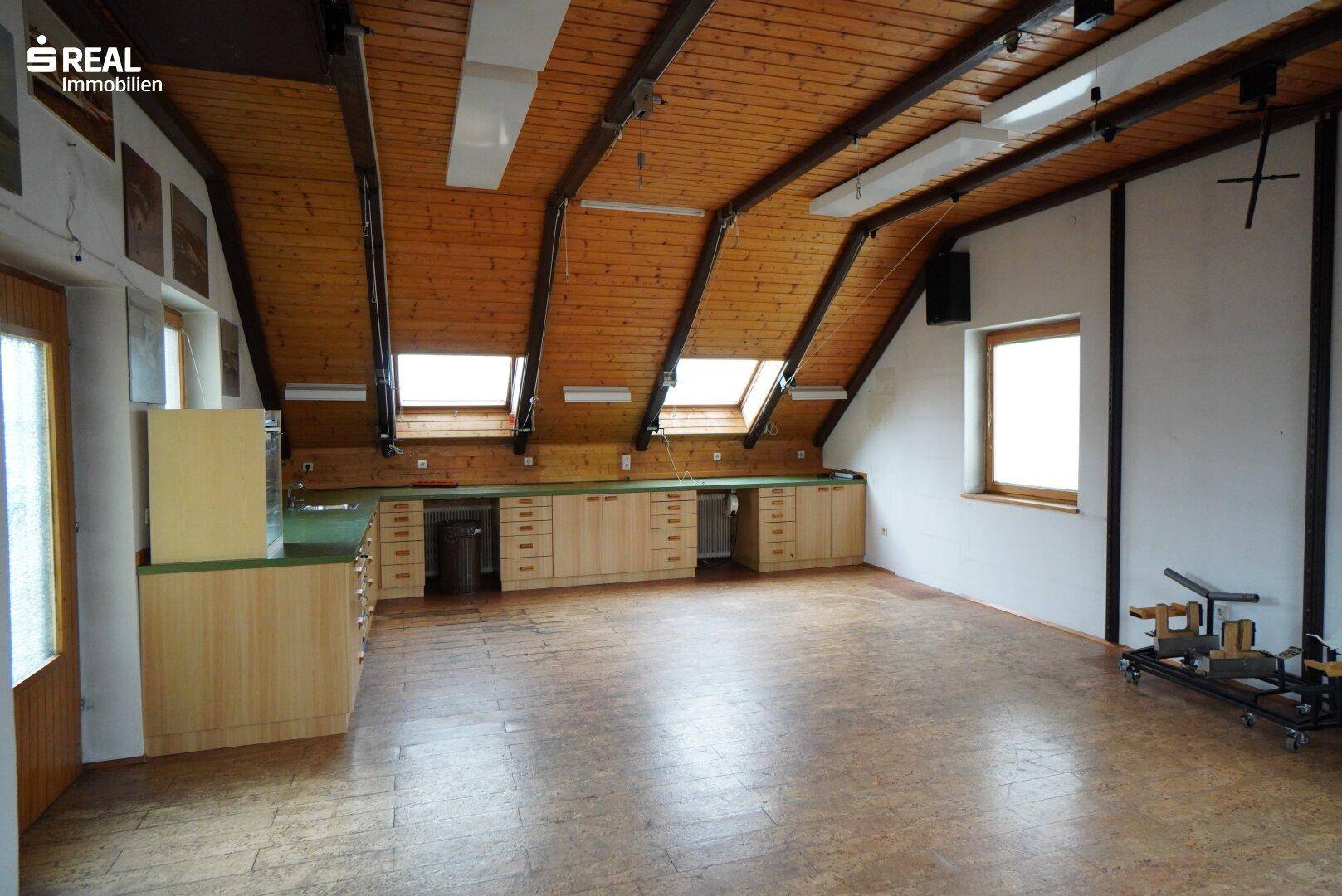 Geräumiger Dachbodenraum mit Holzbalkendecke, mehreren Dachfenstern und langer Arbeitsfläche.