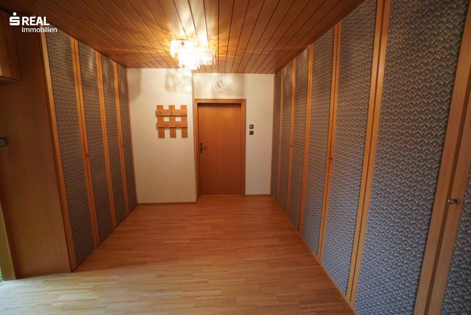 Geräumiger Flur mit Holzdecke, Dielenboden und dekorativen Wandpaneelen.