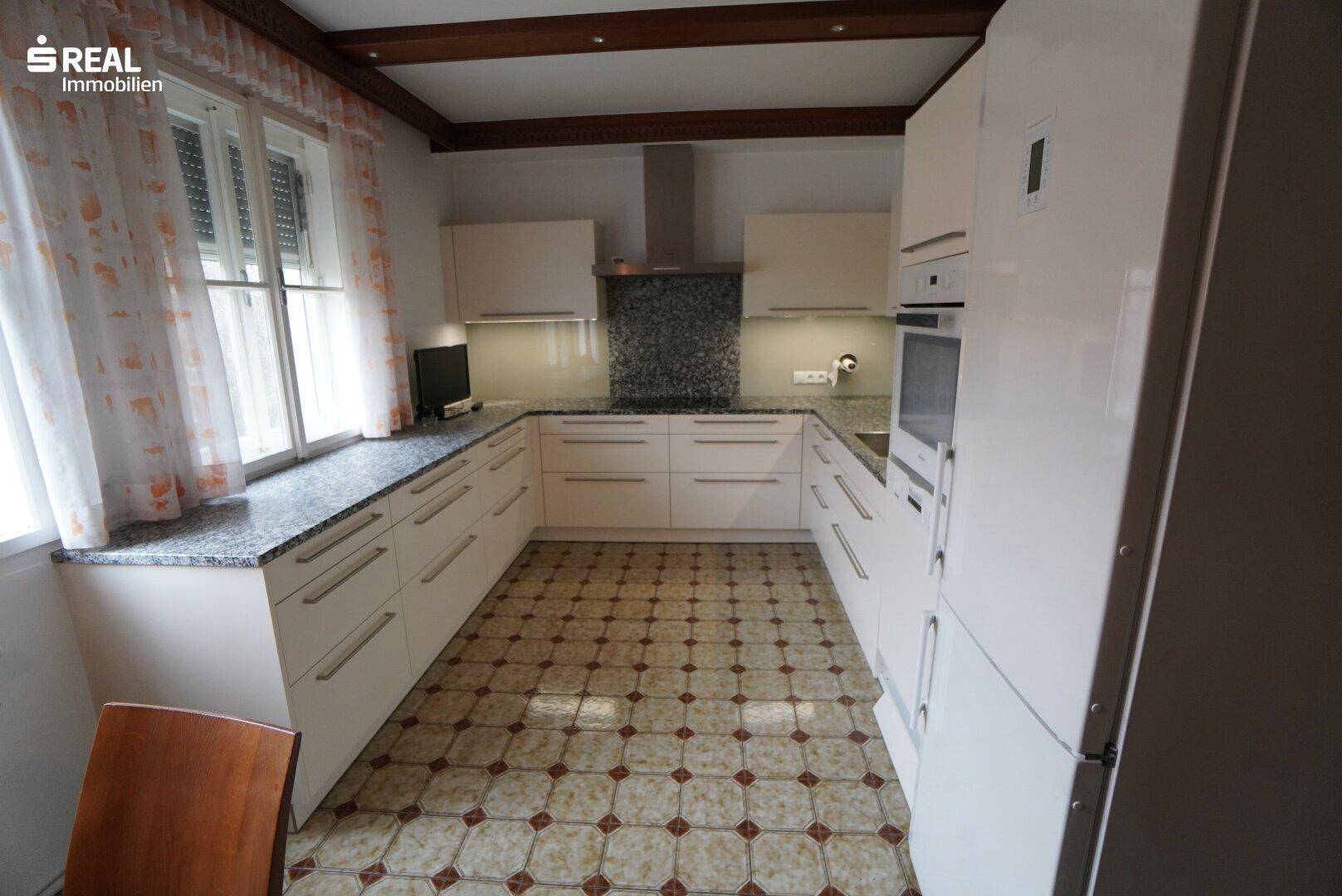 Moderne Küche mit weißen Schränken, Granitarbeitsplatten und Fliesenboden.