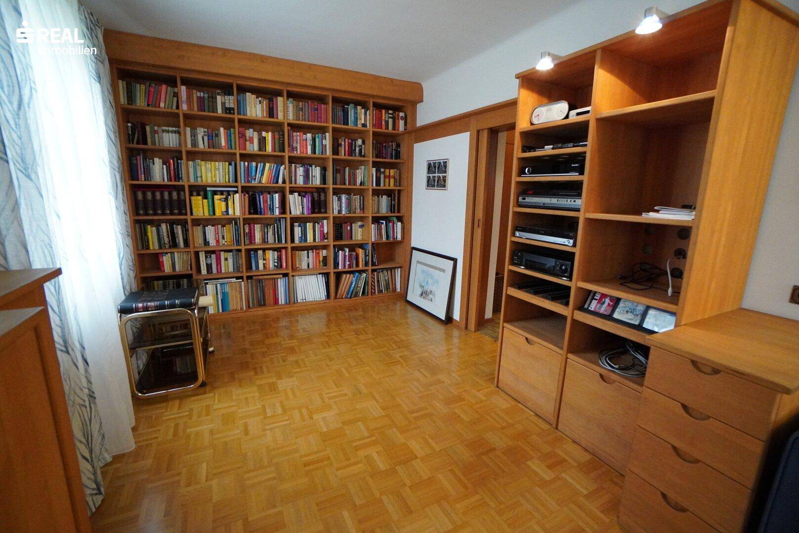 Bibliothek oder Arbeitszimmer mit raumhohem Bücherregal und Parkettboden.