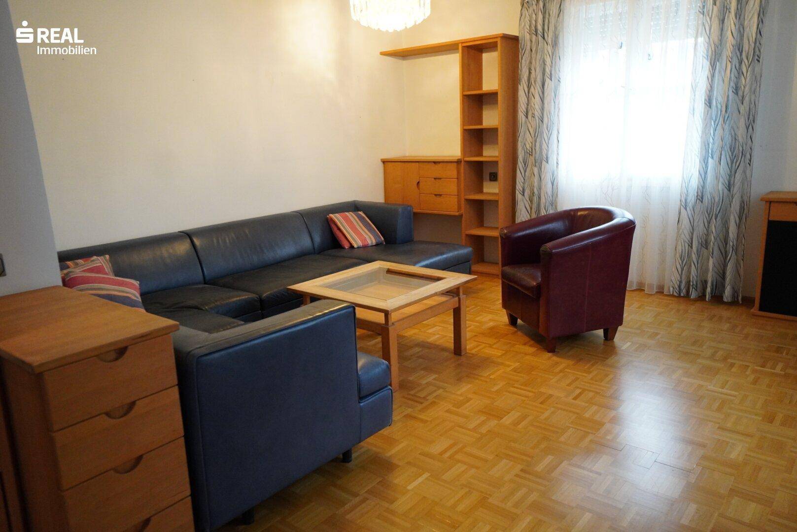 Helles Wohnzimmer mit Parkettboden, Ledersofa und gemütlichem Sessel.